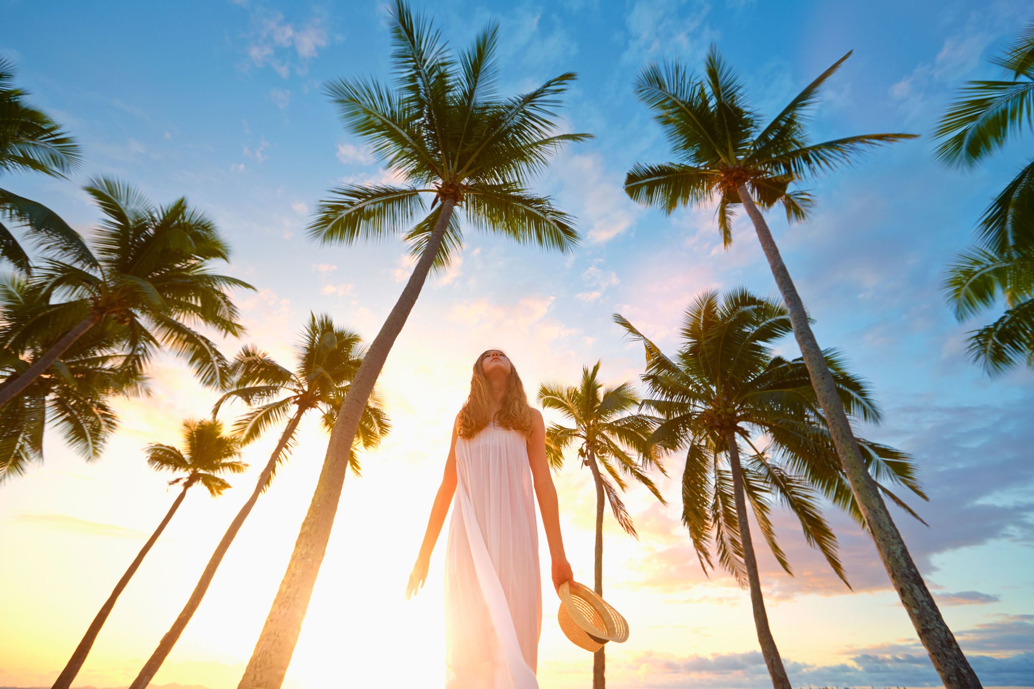 lady wearing white walking by palm trees