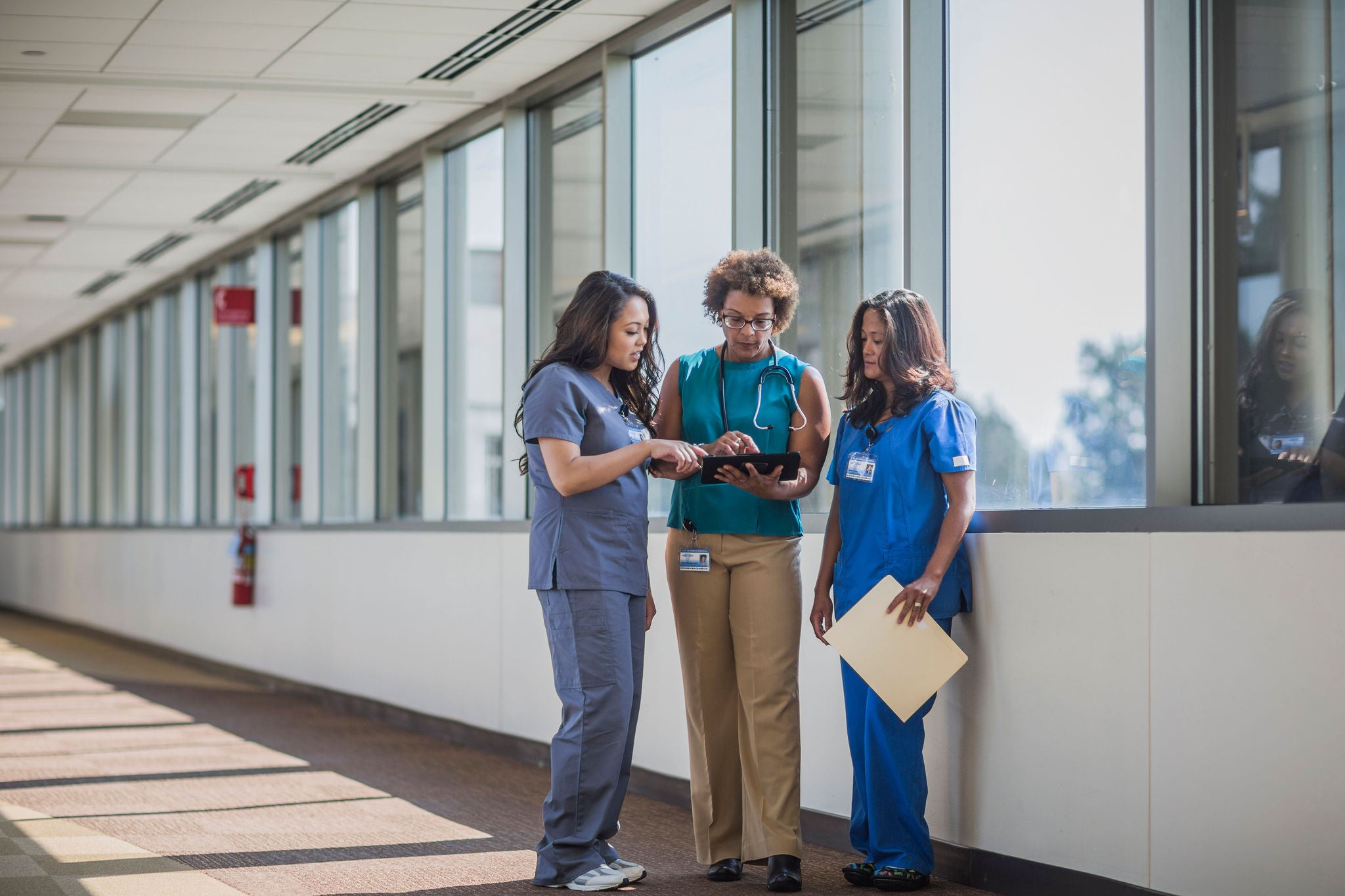 Nurses speak with doctor looking at digital tablet