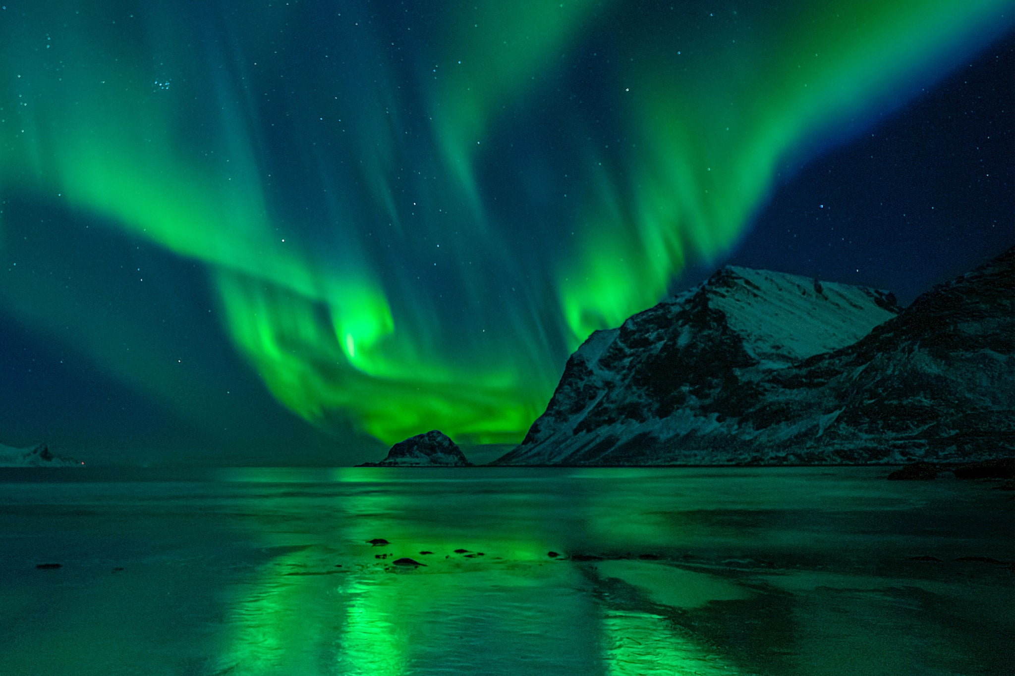 wonderful night sky with aurora borealis over a beach with reflections, lofoten, norway