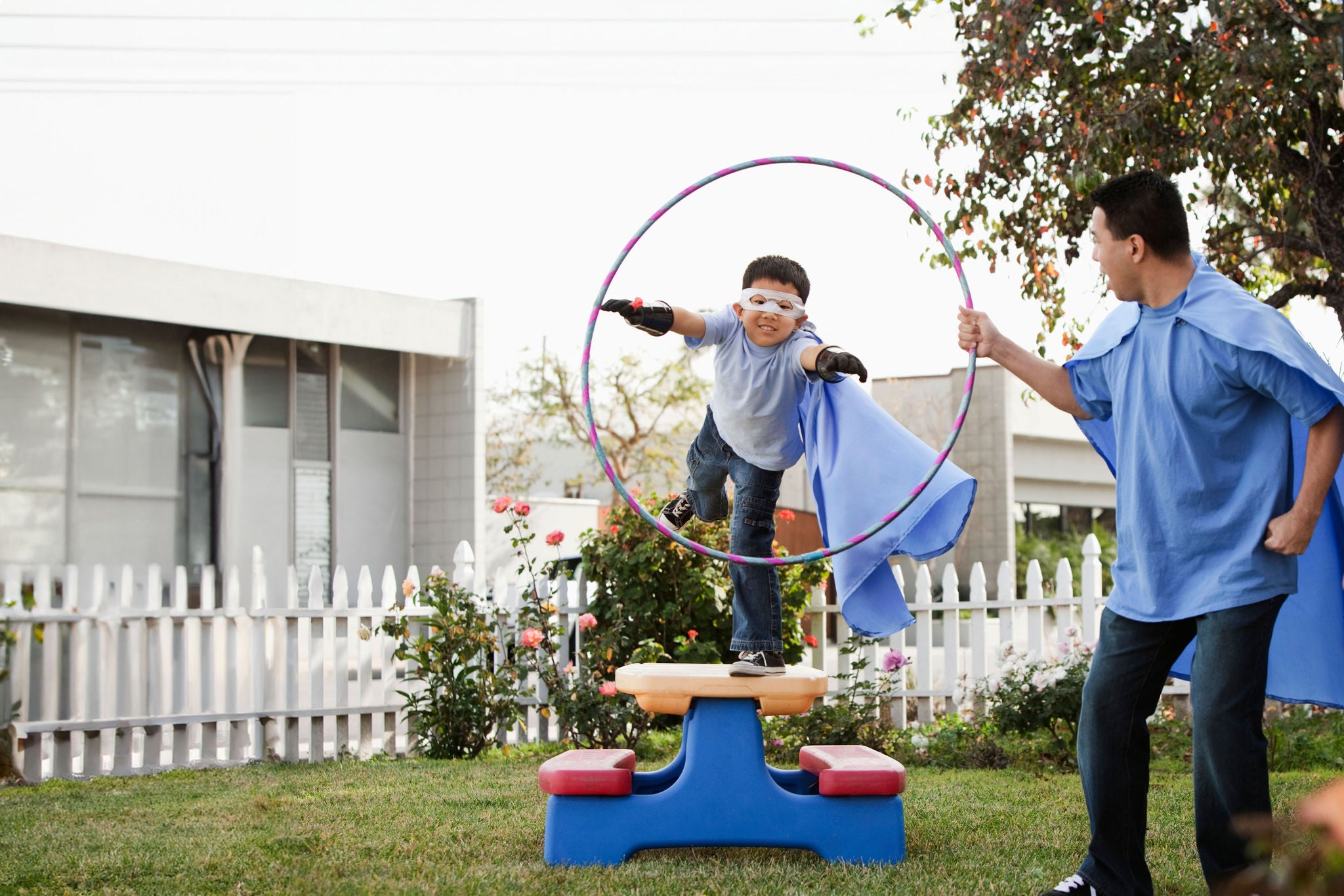 Boy in superhero costume jumping through hoop