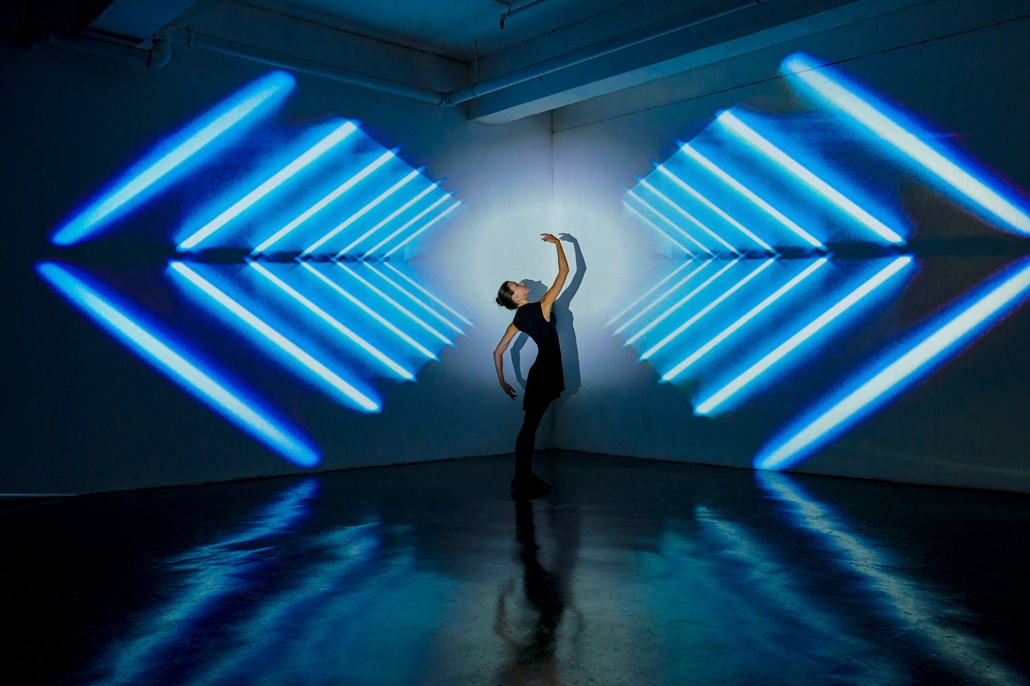 Girl dancing in a studio with graphic patterns projected onto her
