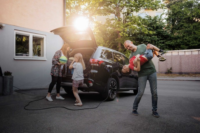 family standing besides electric car