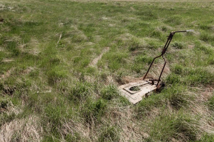 A lawnmower missing it engine, rots in a field