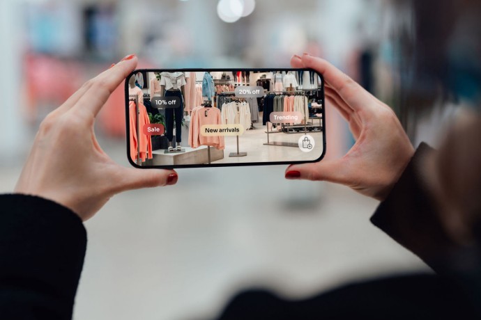 Hands holding smartphone using augmented reality application to check sales in fashion store