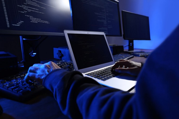 Hacker with computers in dark room