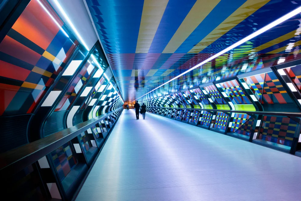 Interior of pedestrian tunnel illuminated at night at the new Crossrail station at Canary Wharf. The lighting was designed by French  artist 'Camille Walala' at Canada Place