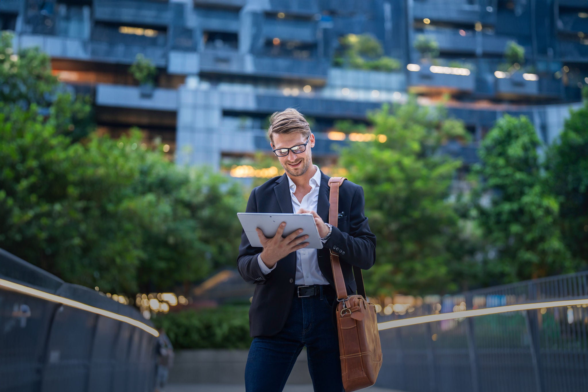 Man looks at tablet while walking outside in a tech park