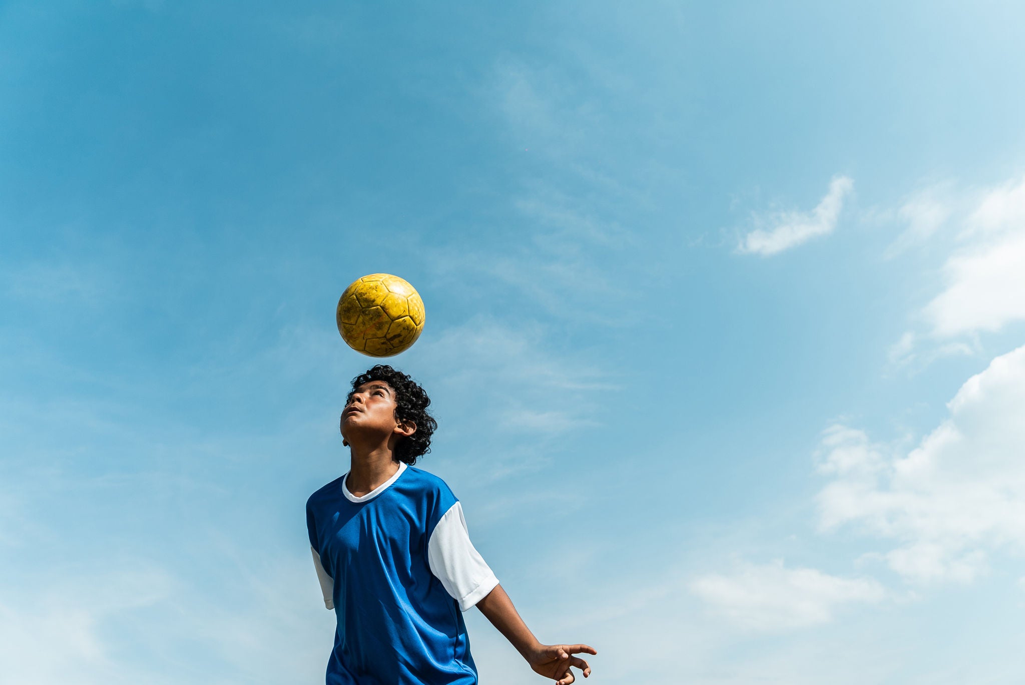 garoto cabeceando uma bola