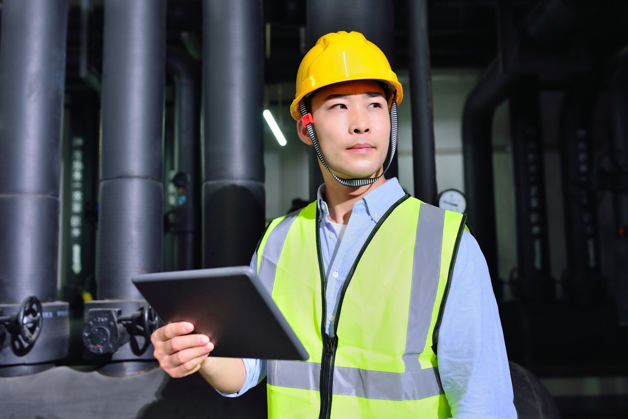 Man standing and holidng tablet at factory