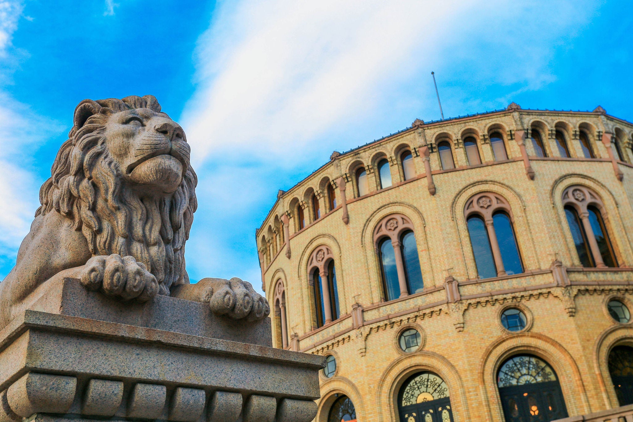 Bilde av Stortinget i Karl Johan med blå himmel og liggende løve.