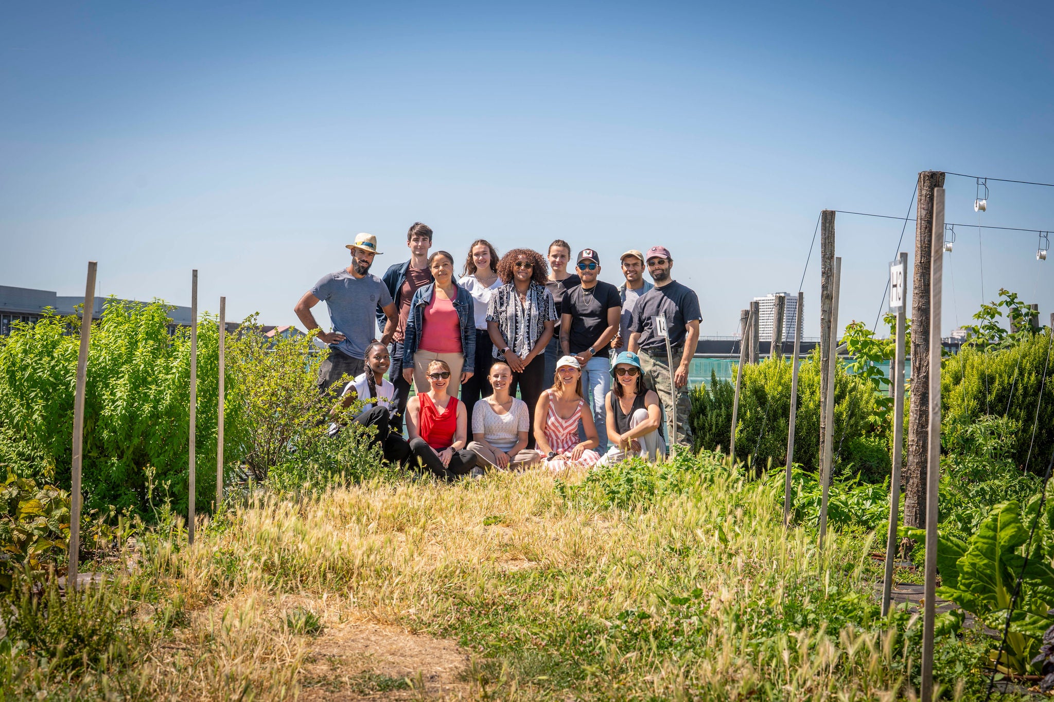 Groupe posant dans jardin urbain avec plantes et treillis