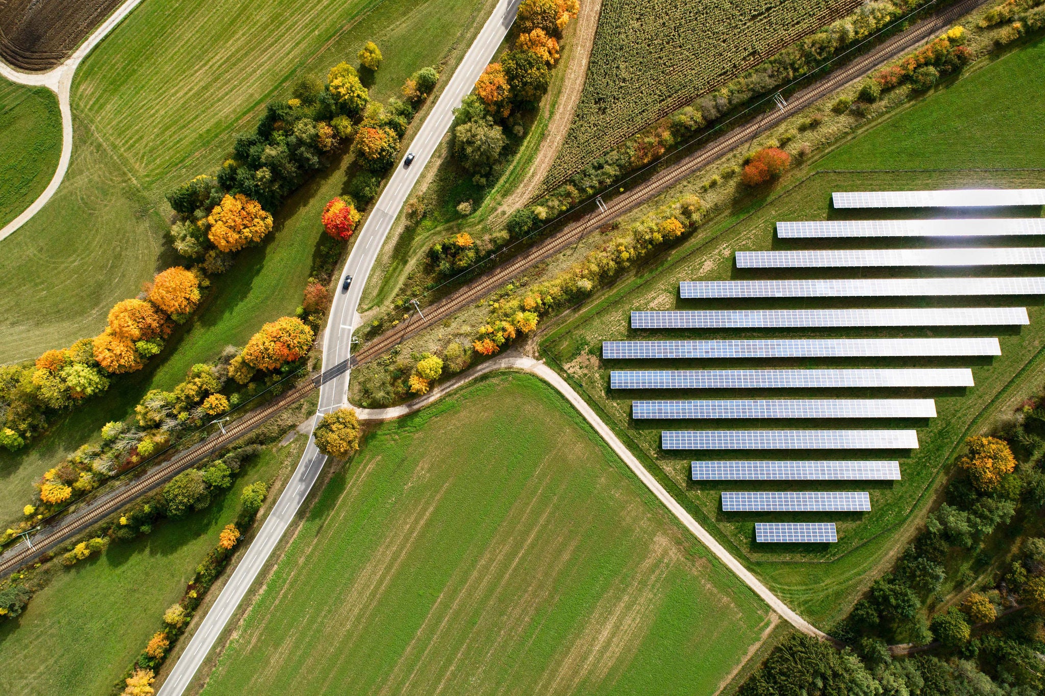 Aerial view of a highway crossing railroad tracks in Autumn , solar panels