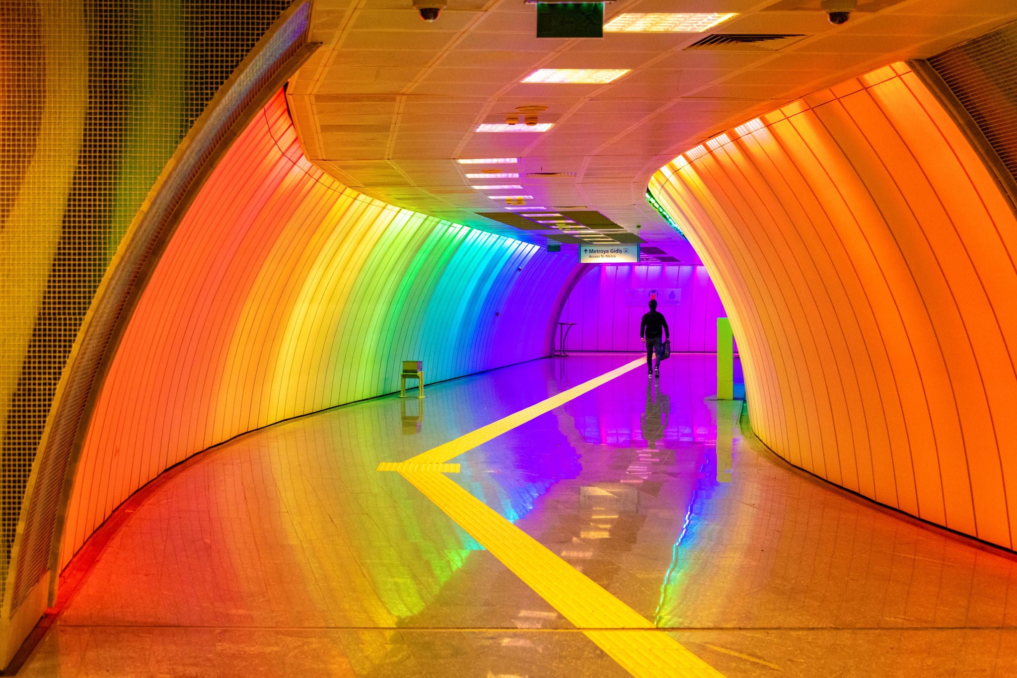 Commuters walking toward the underground in colorfully lit Levent station