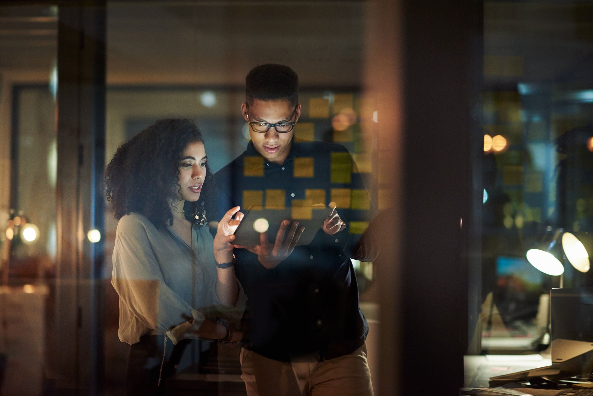 Shot of a young businessman and businesswoman using a digital tablet during a late night at work