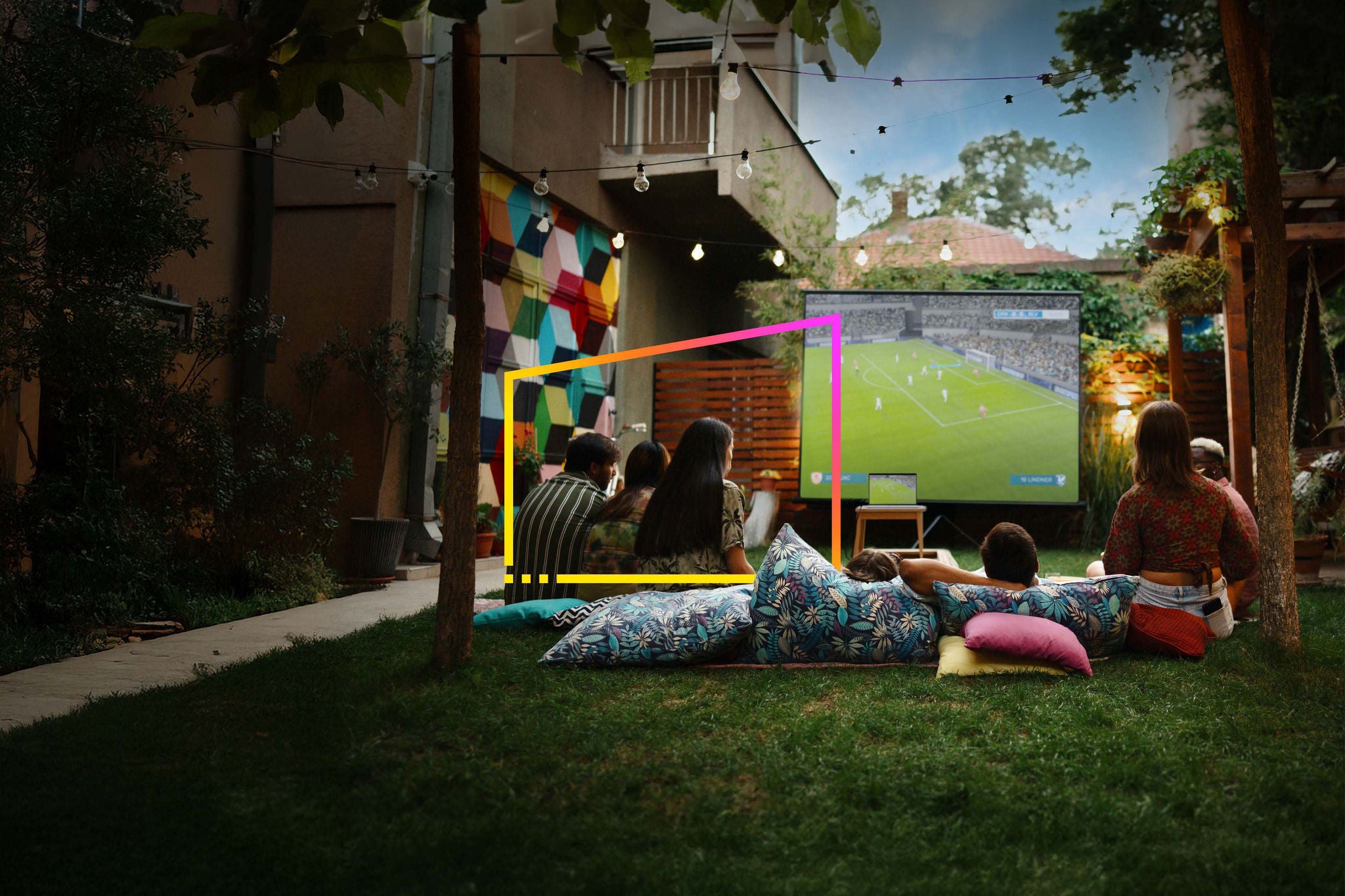 Joyful friends watching movies on a projection screen  in the backyard