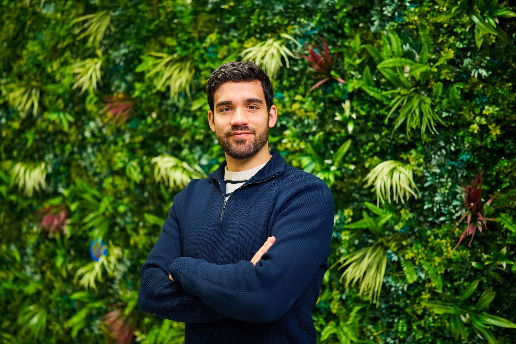 Professional standing before a lush indoor green wall