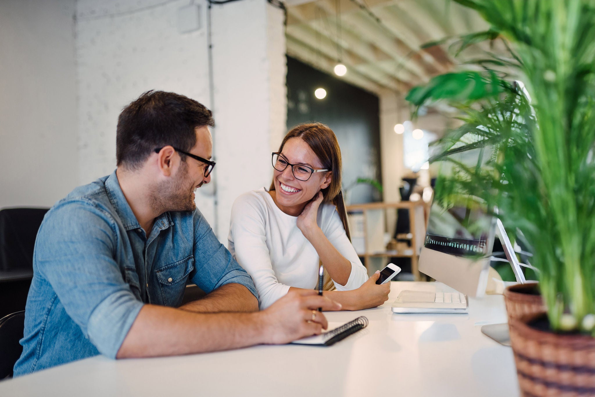 Two smiling colleagues talking in modern open space office.