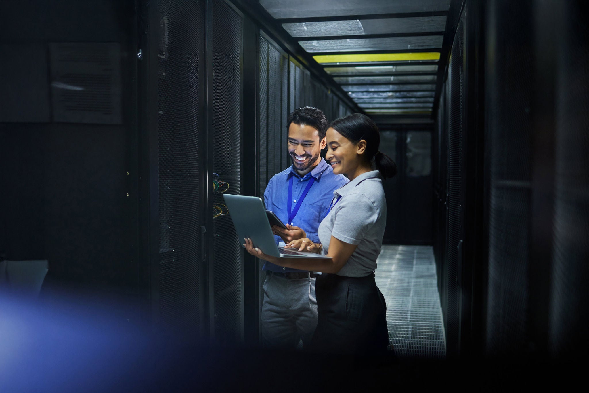 Server room, laptop and technician people for software management, system upgrade or cyber security.