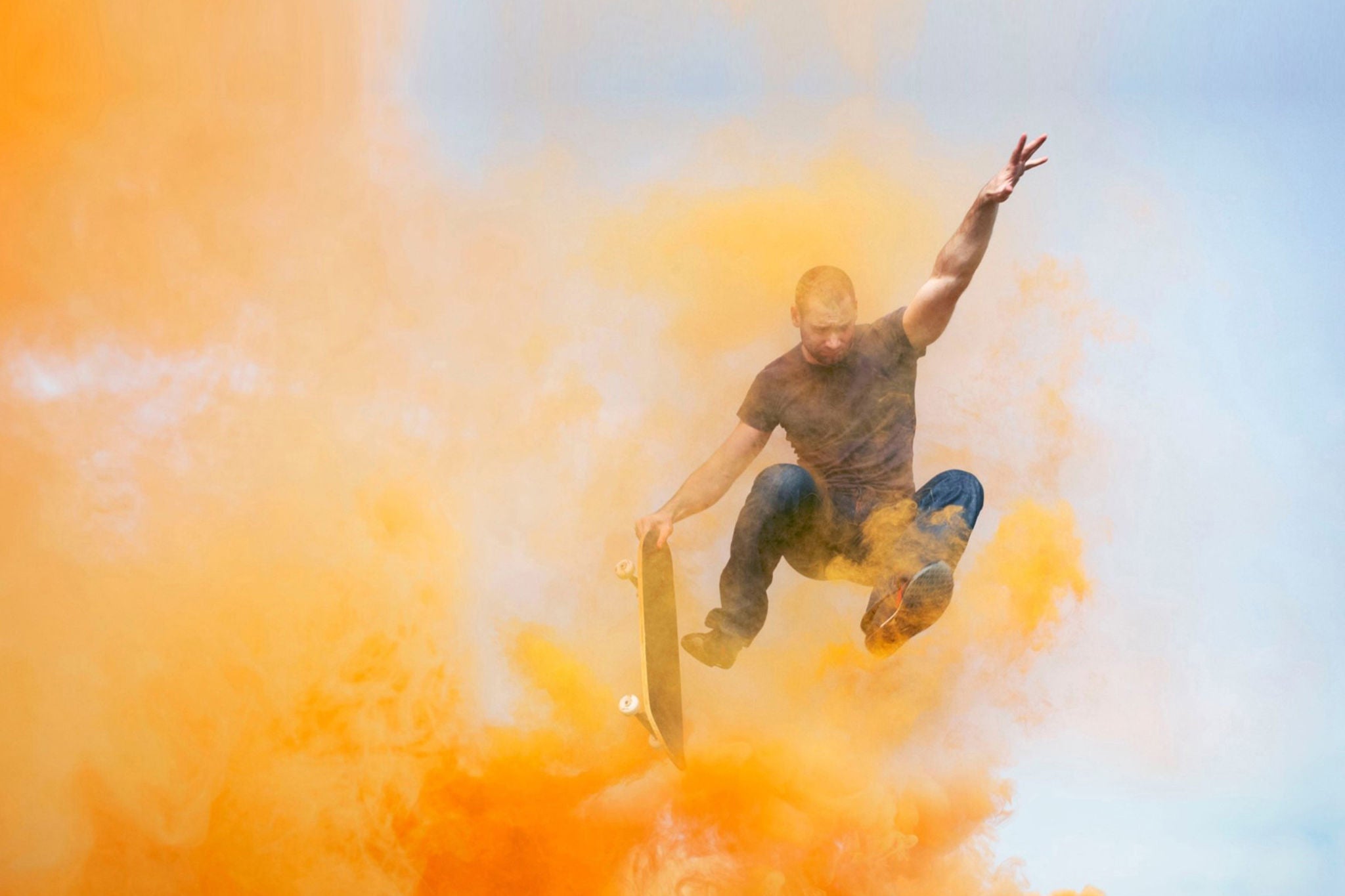 EY Man jumping through orange smoke with skateboard 