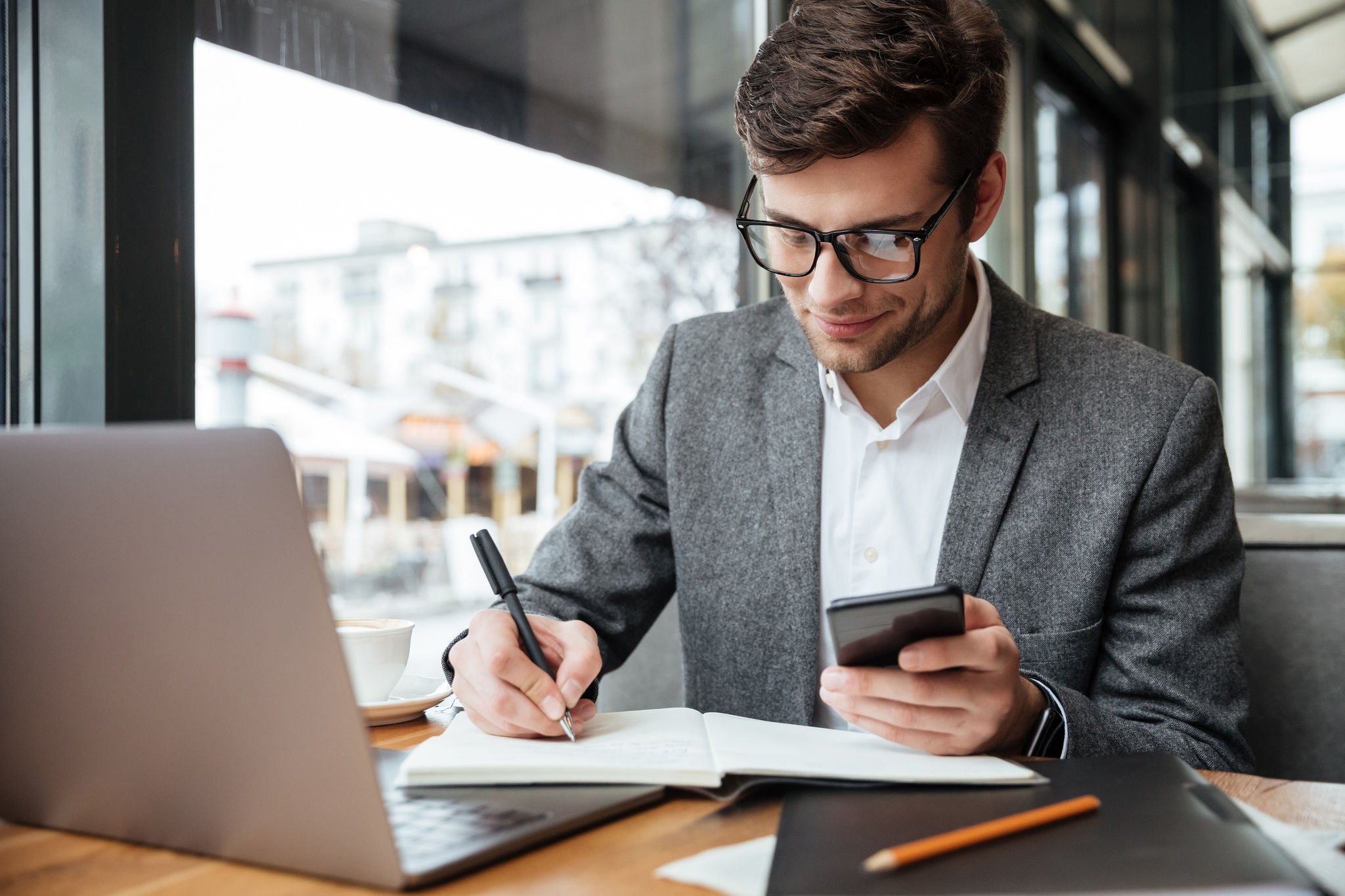 Smiling business man in eyeglass sitting by table in café 