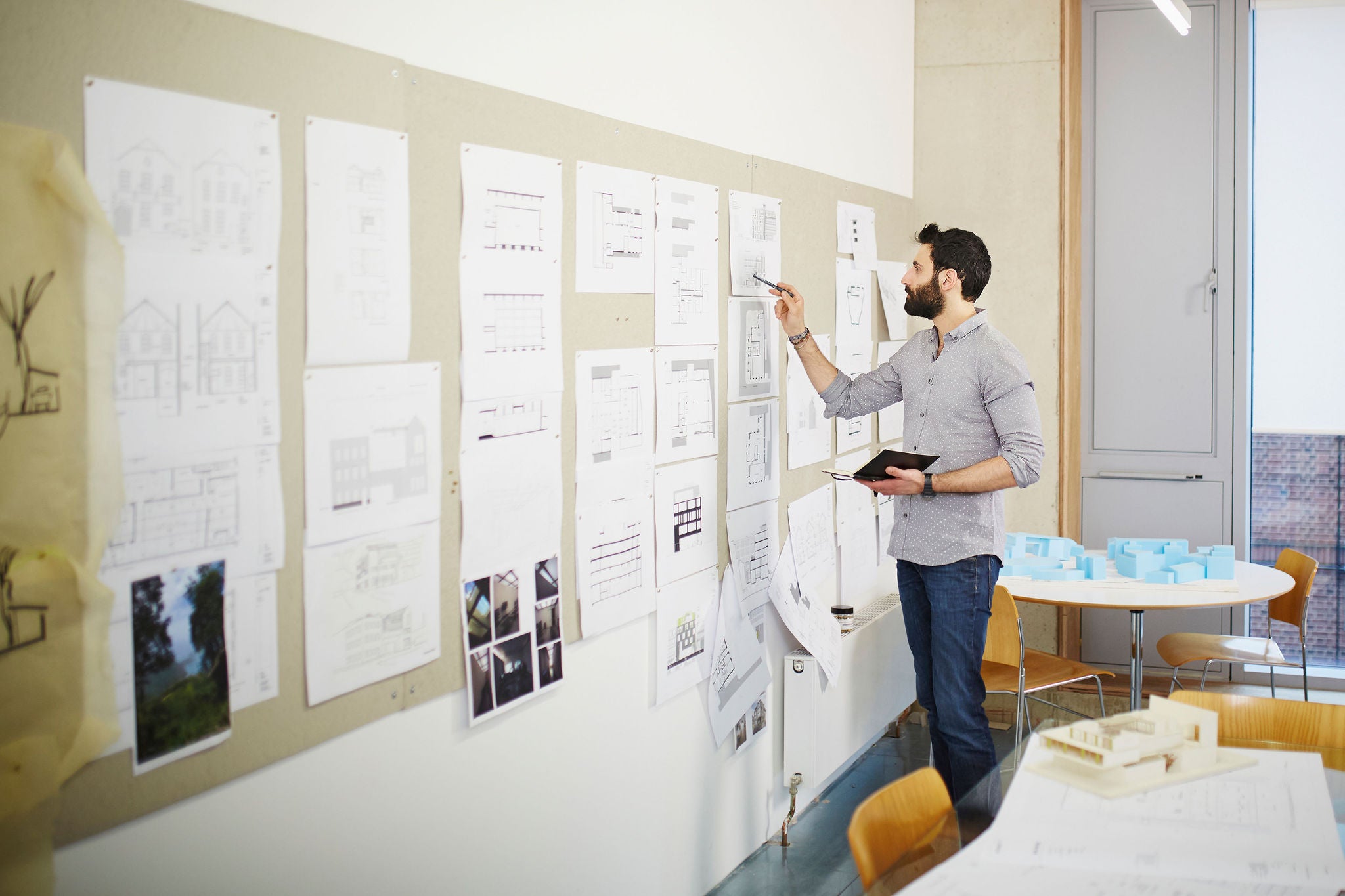 Architect reviews plans on a pinboard in an office
