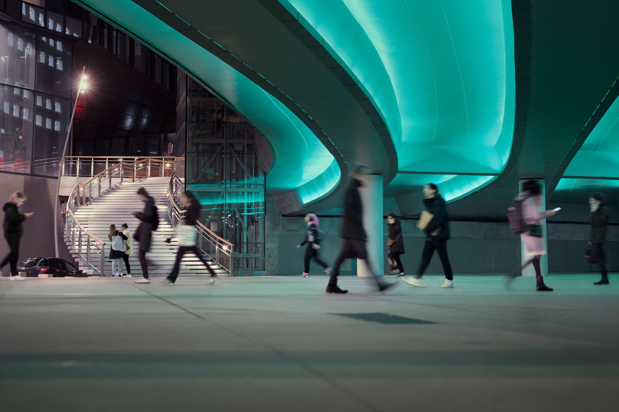 Evening commute with people passing a LED illuminated viaduct