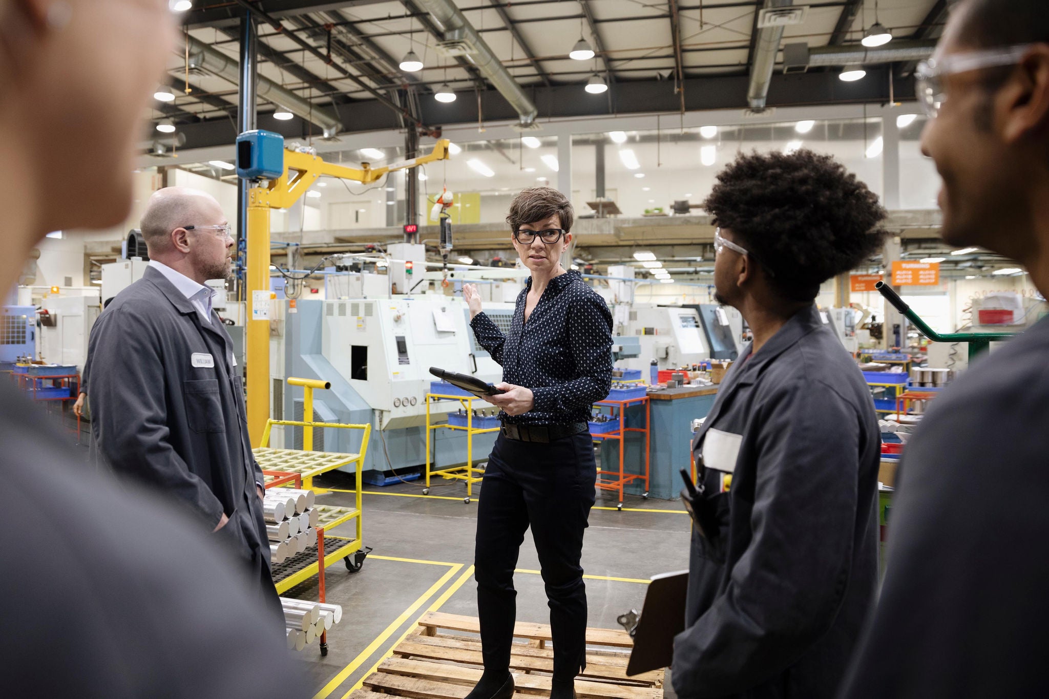 Female supervisor talking with machinists in factory