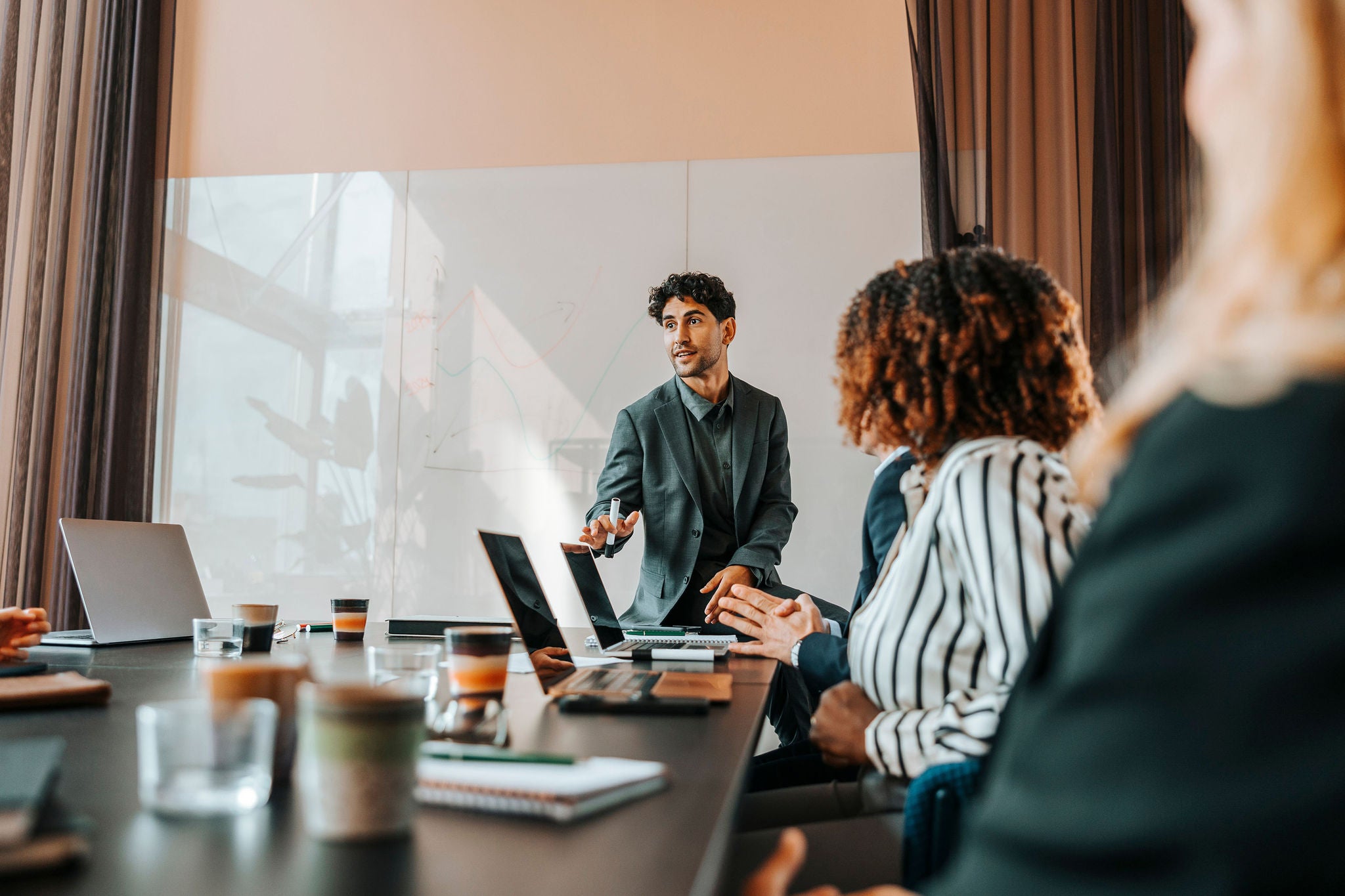 Young male entrepreneur brainstorming colleagues sitting in board room at office