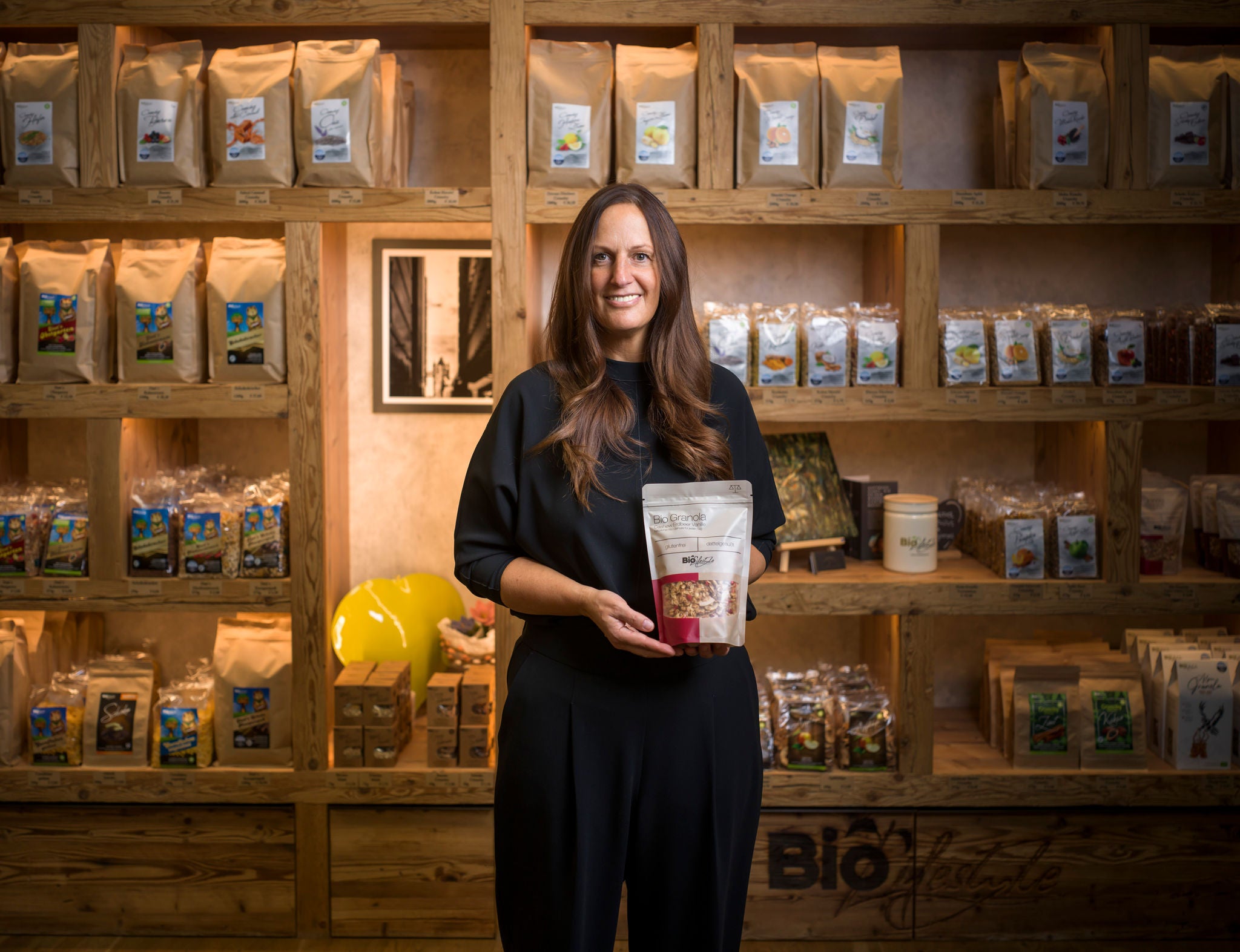 Unternehmerin steht vor Produktwand und hält ein Müsli in der Hand