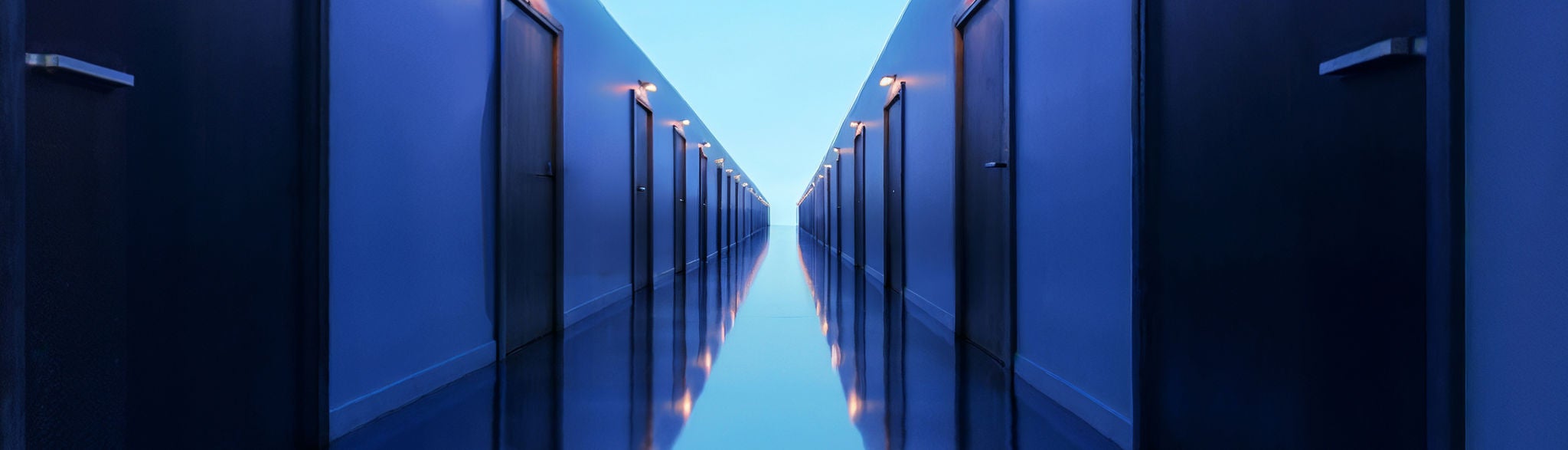 Futuristischer, blau beleuchteter Korridor mit symmetrischen Türen und reflektierendem Boden.