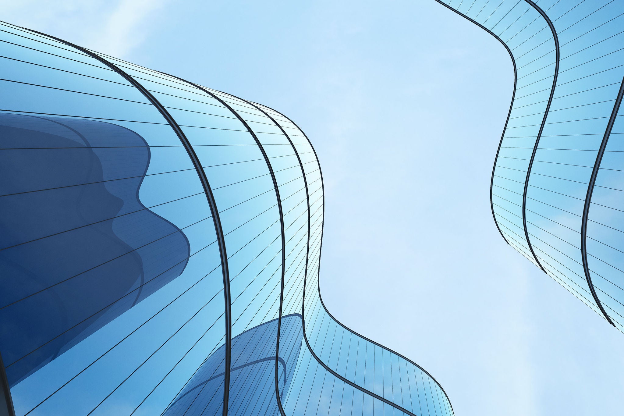 Abstrakte Ansicht moderner Bürogebäude mit geschwungenen Glasfassaden vor blauem Himmel.