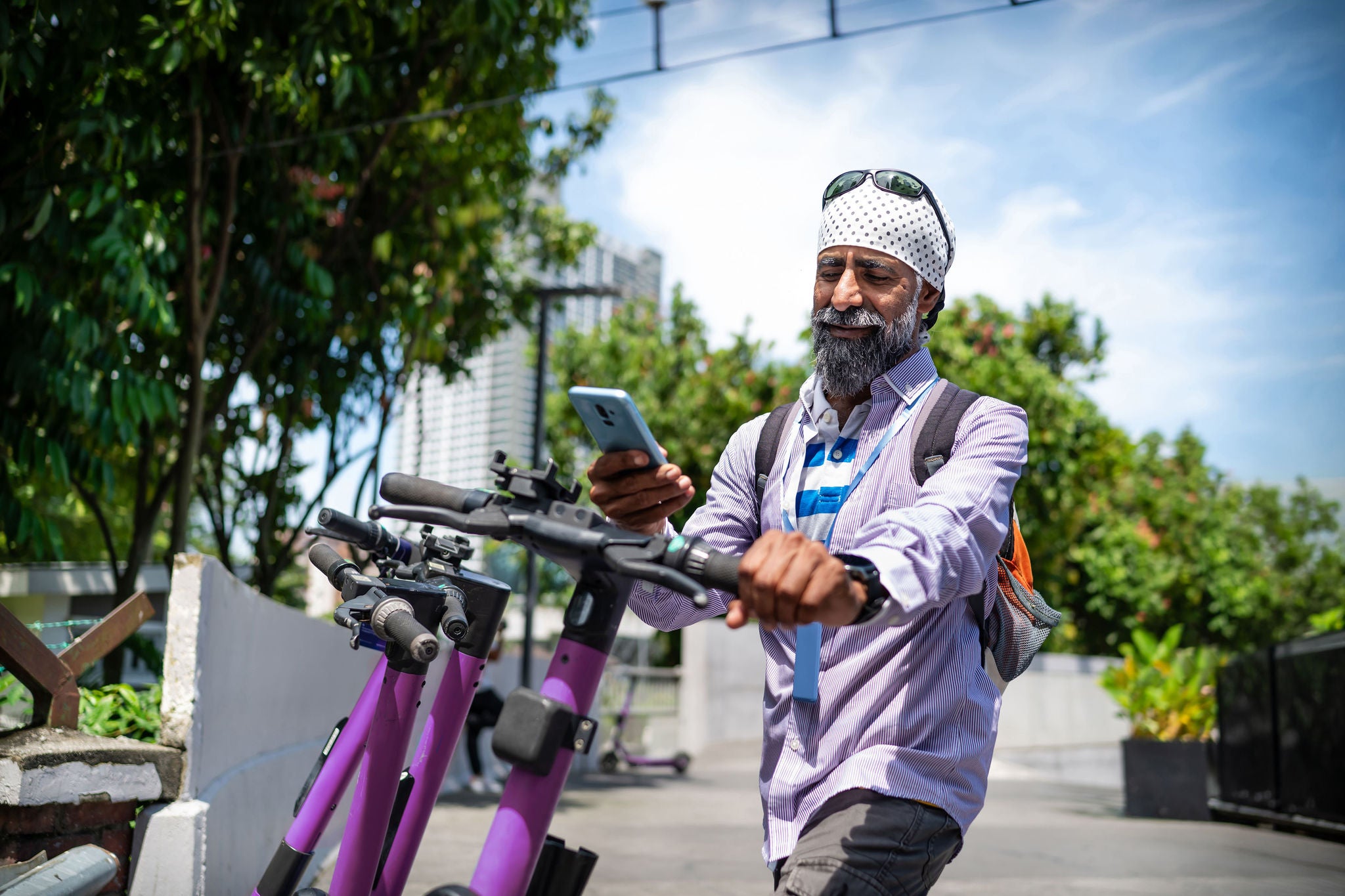 senior Sikh man using smart phone to unlock the electric scooter