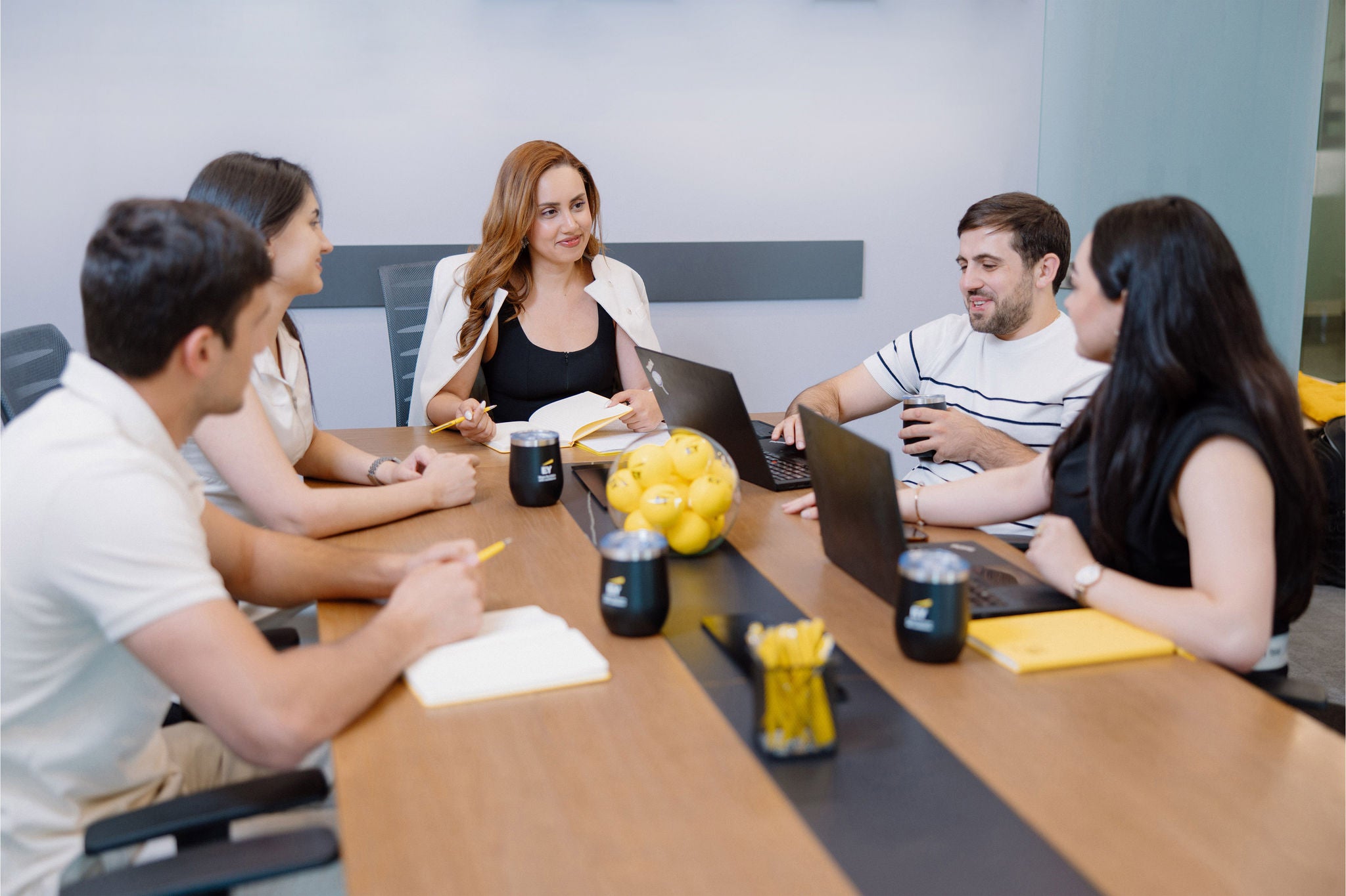 Team meeting around a conference table with laptops and notebooks.
