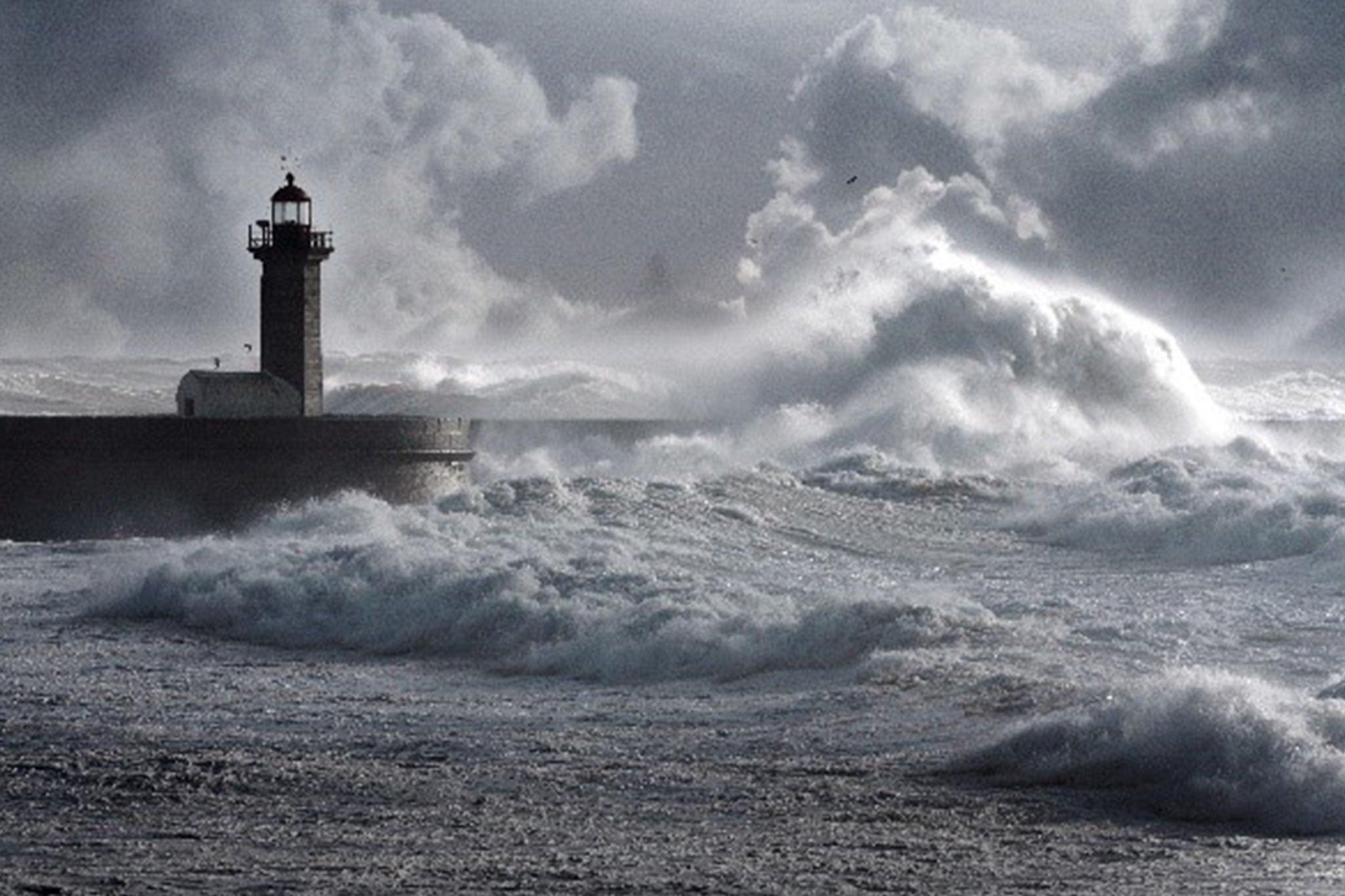 Huge waves crashing against a lighthouse in a storm