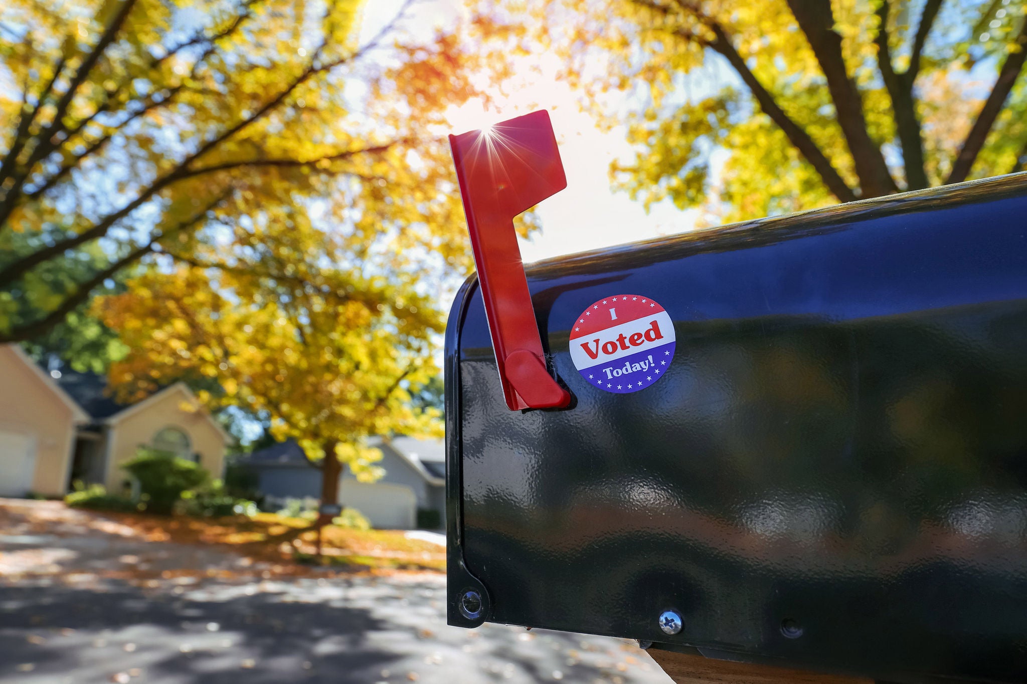 Mailbox with an "I voted today" sticker on it with sun flare behind flag, absentee voting through the mail