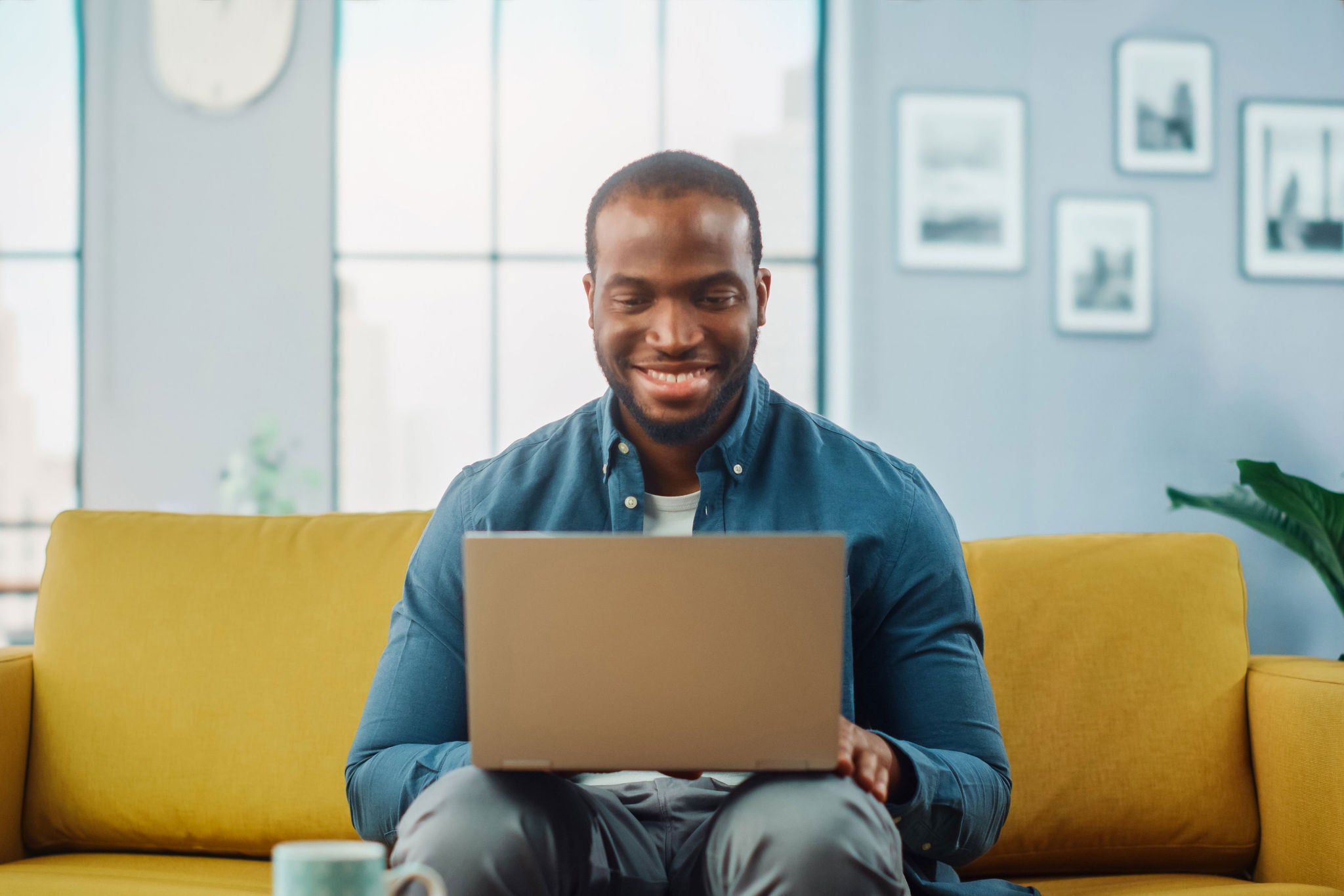 Man smiling at laptop on sofa