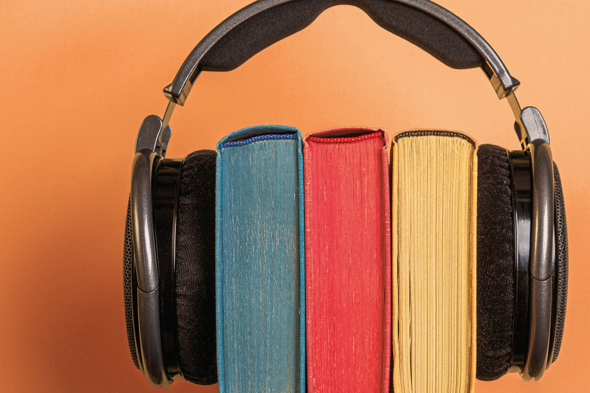 Kopfhörer umschließen farbige Bücher als Symbol für Hörfunk, Podcasts und Wissen zu Steuer- und Rechtsfragen.