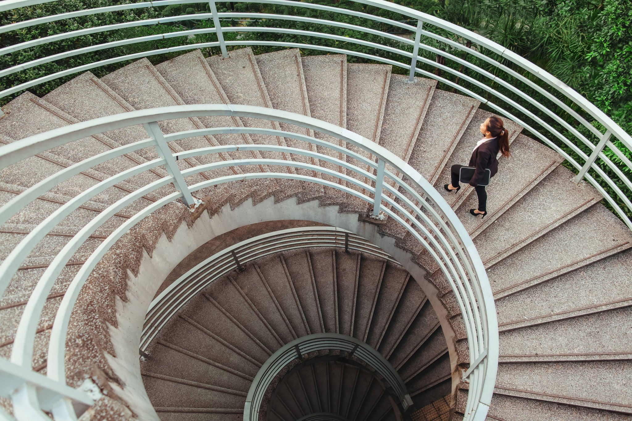 Women carring laptop and walking on the round steps