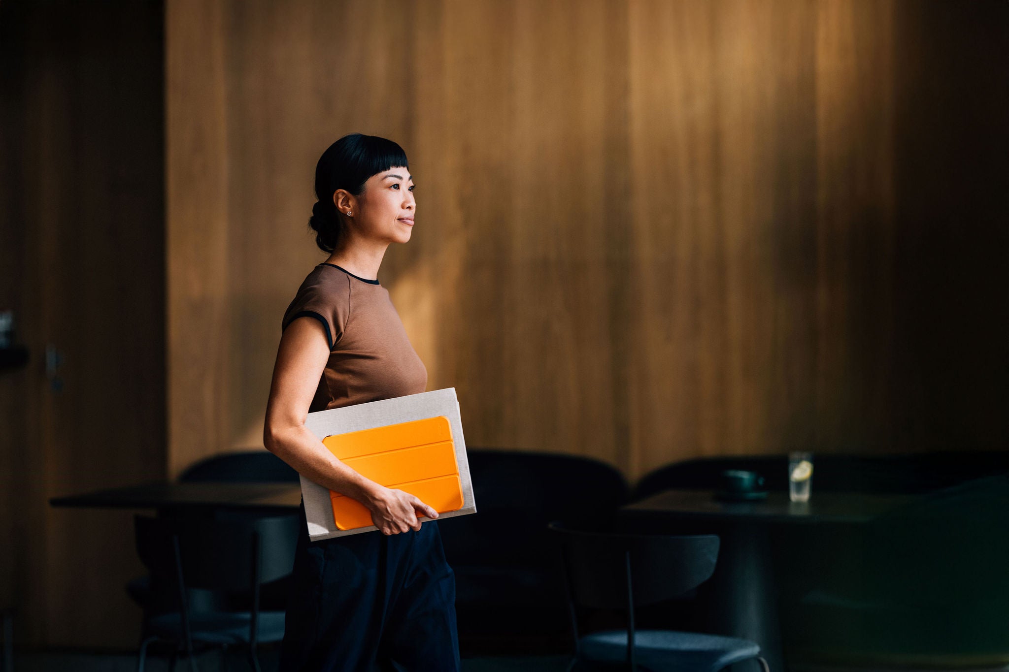 Confident Woman Holding Notebook in Modern Office Environment