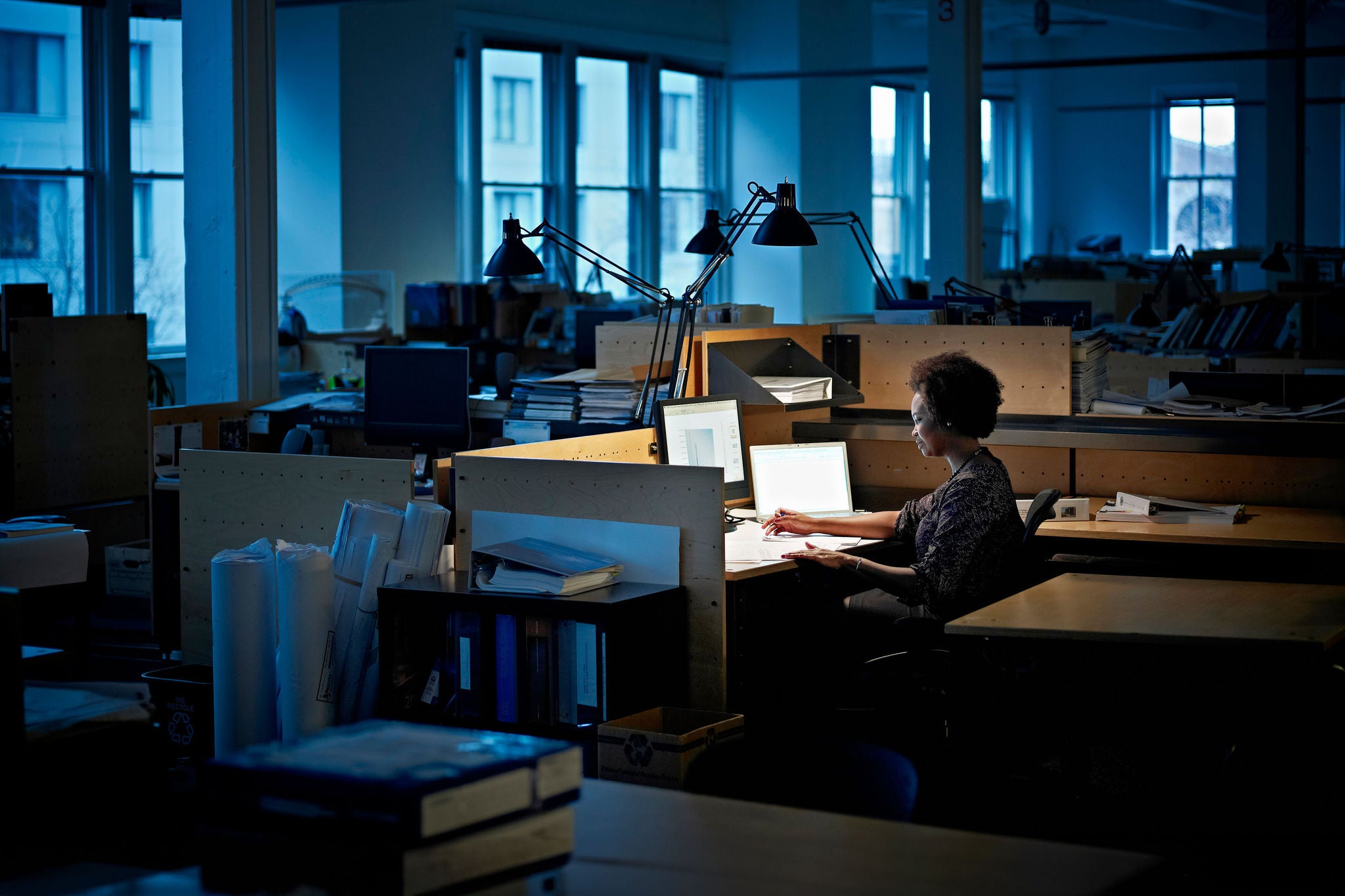 Businesswoman working at desk examining documents in empty office at night