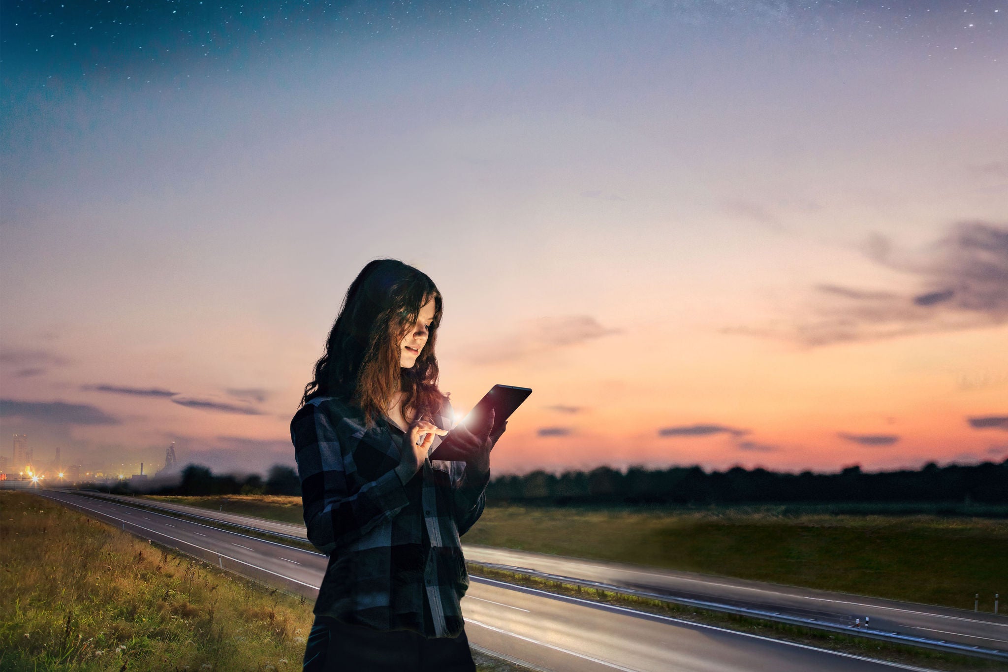 female using digital tablet while examining a highway at dusk