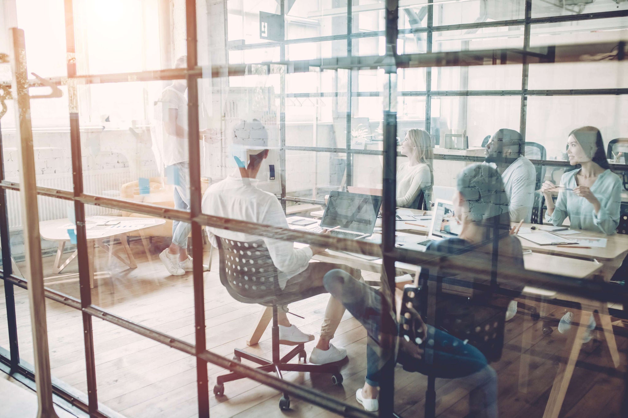 A group of people having a meeting in a glass conference room