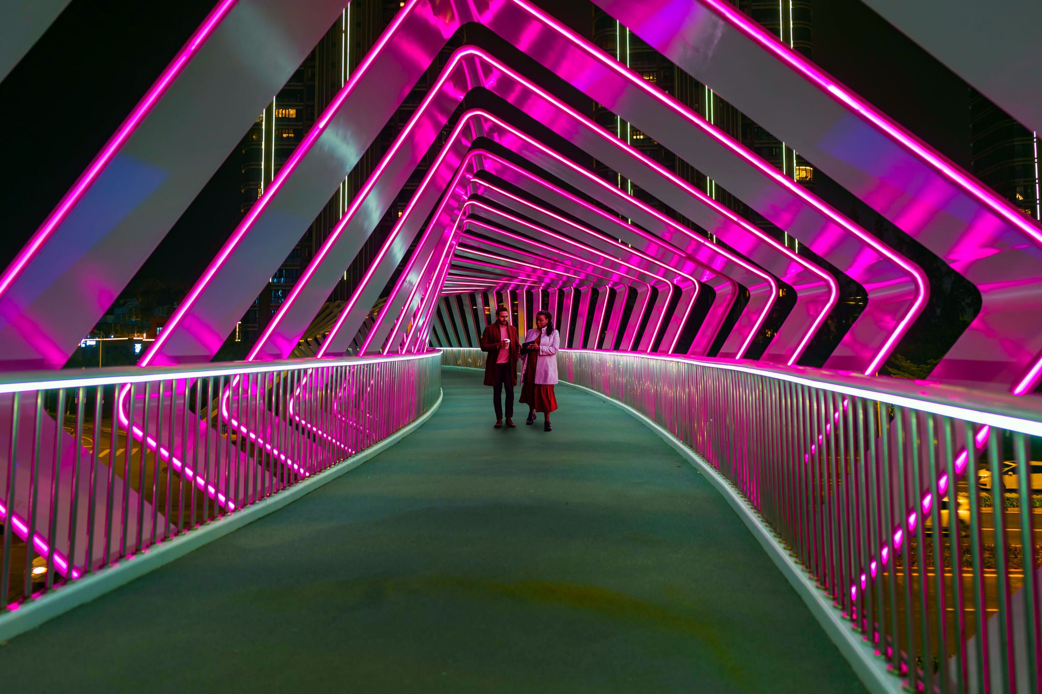 Two people walk along a pink pedestrian bridge at Chuanggu Road