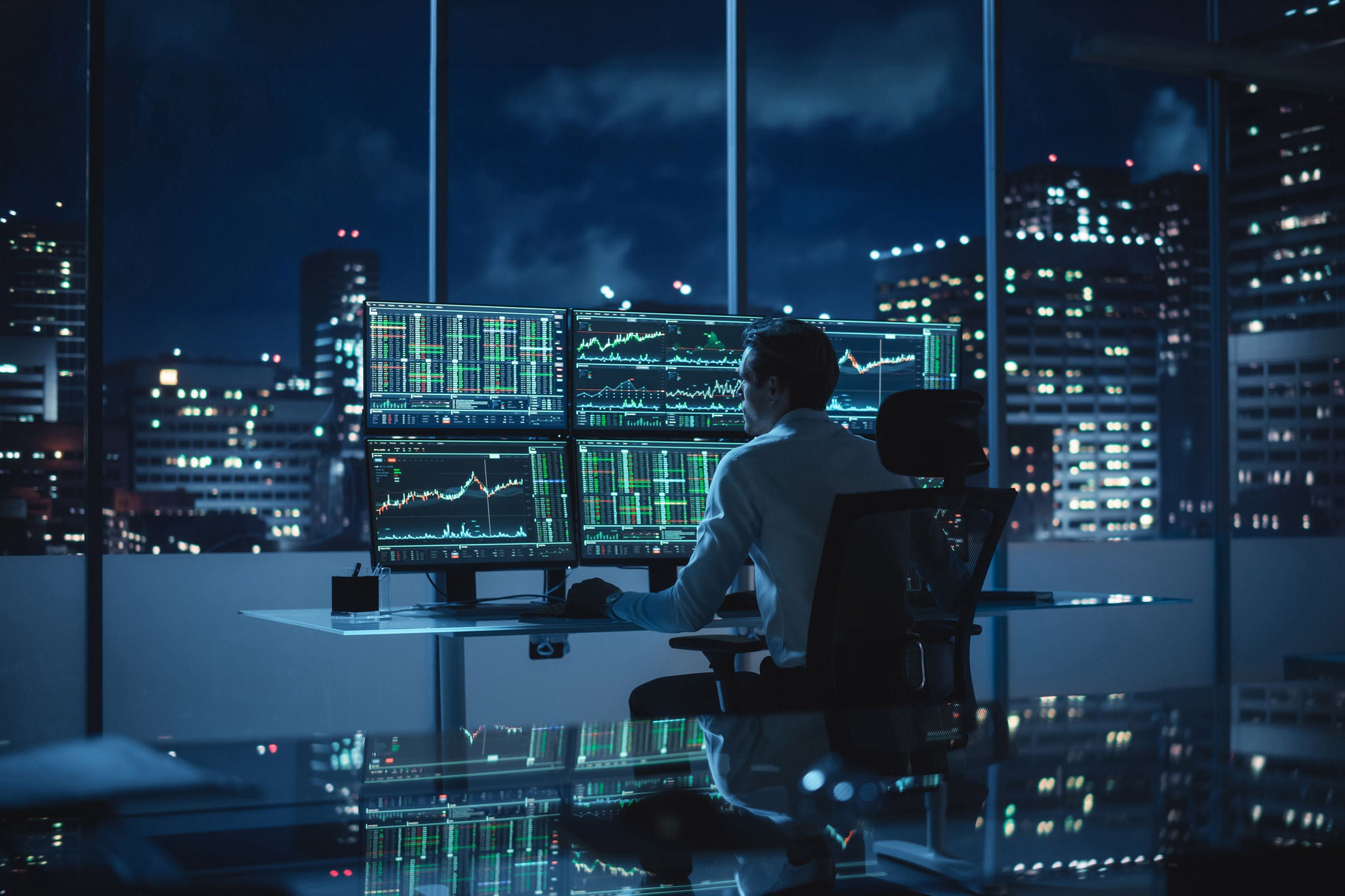 Financial analyst at a multi‑monitor desk reviewing real‑time stock and commodity charts, planning next investment.