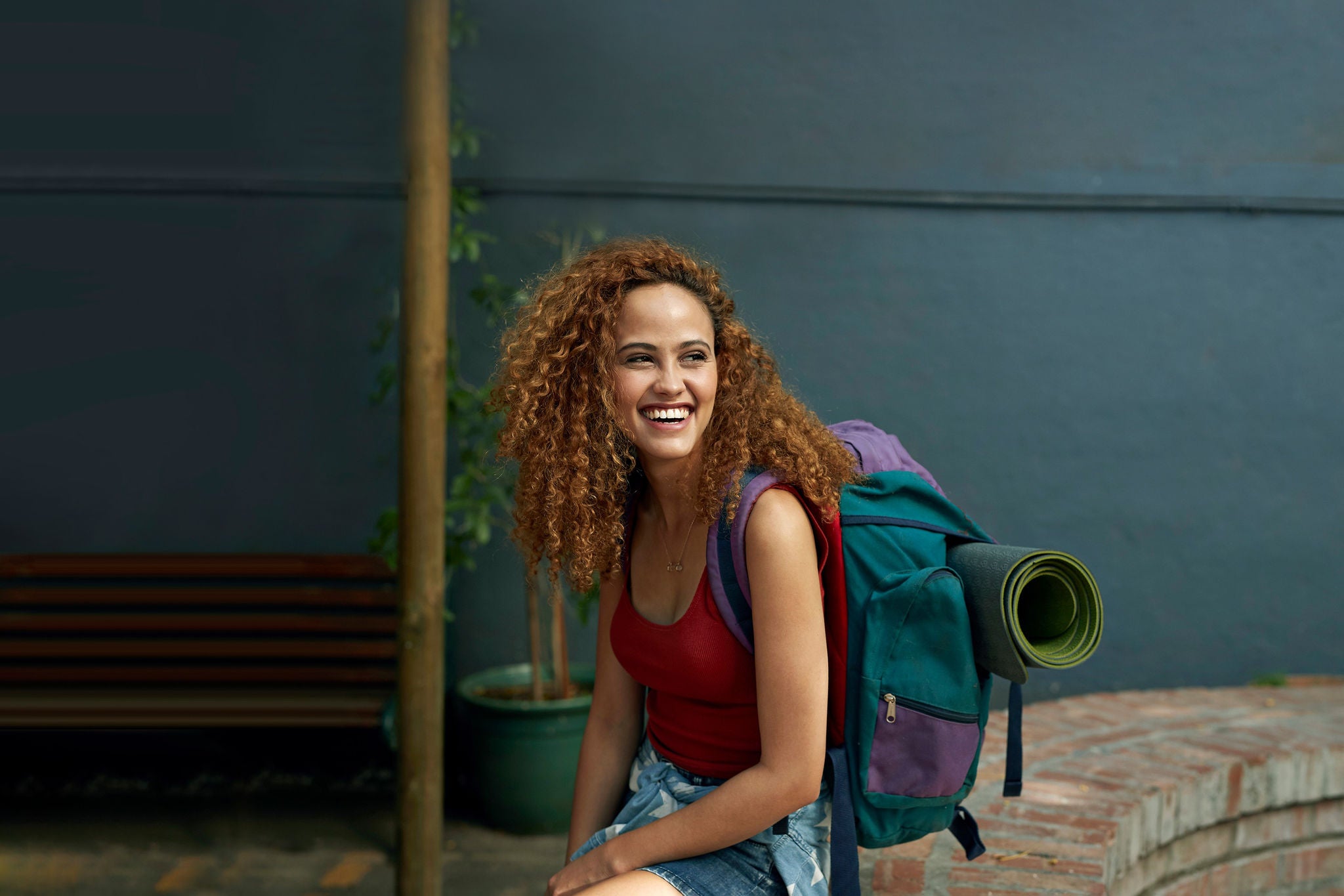 Young woman with backpack sitting in courtyard