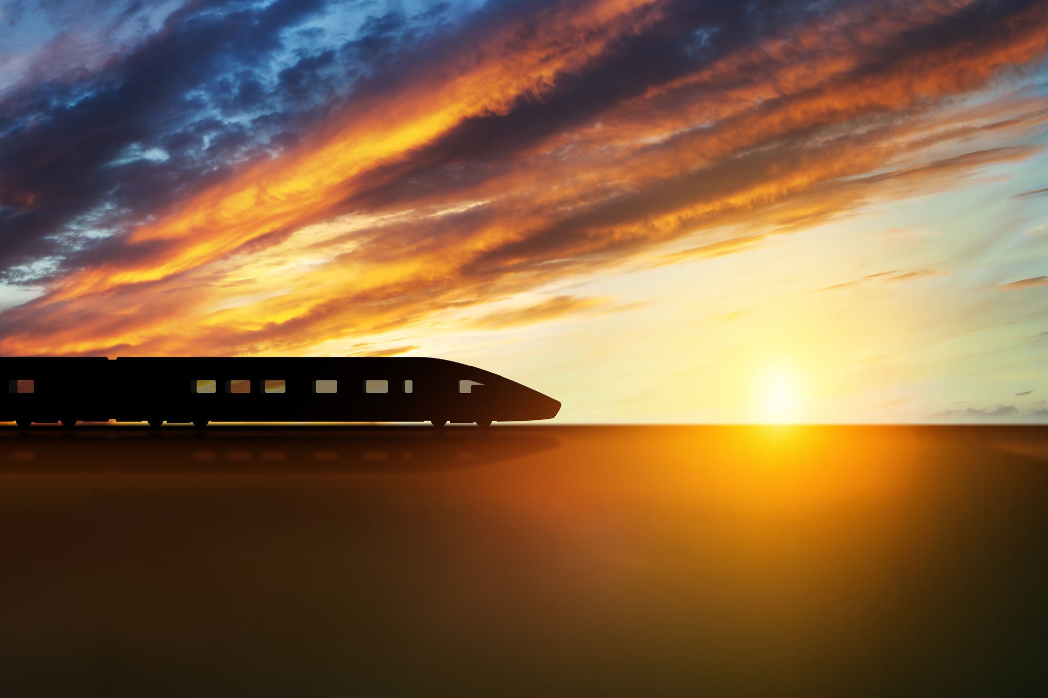 High speed train silhouette in motion at sunset. Fast moving modern passenger train on railway platform. Commercial transportation.