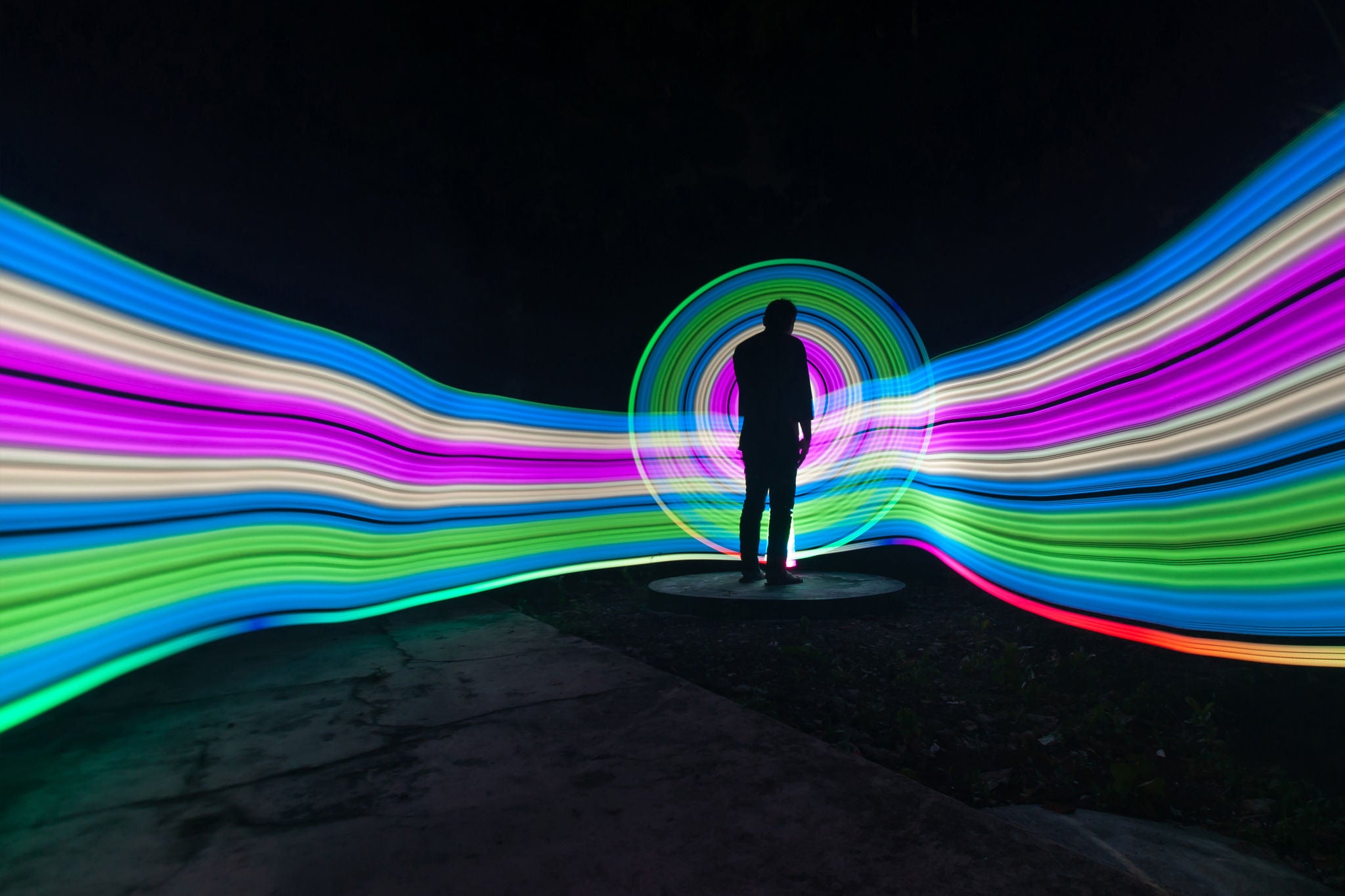 One person standing alone against beautiful color circle LED light painting as the backdrop
