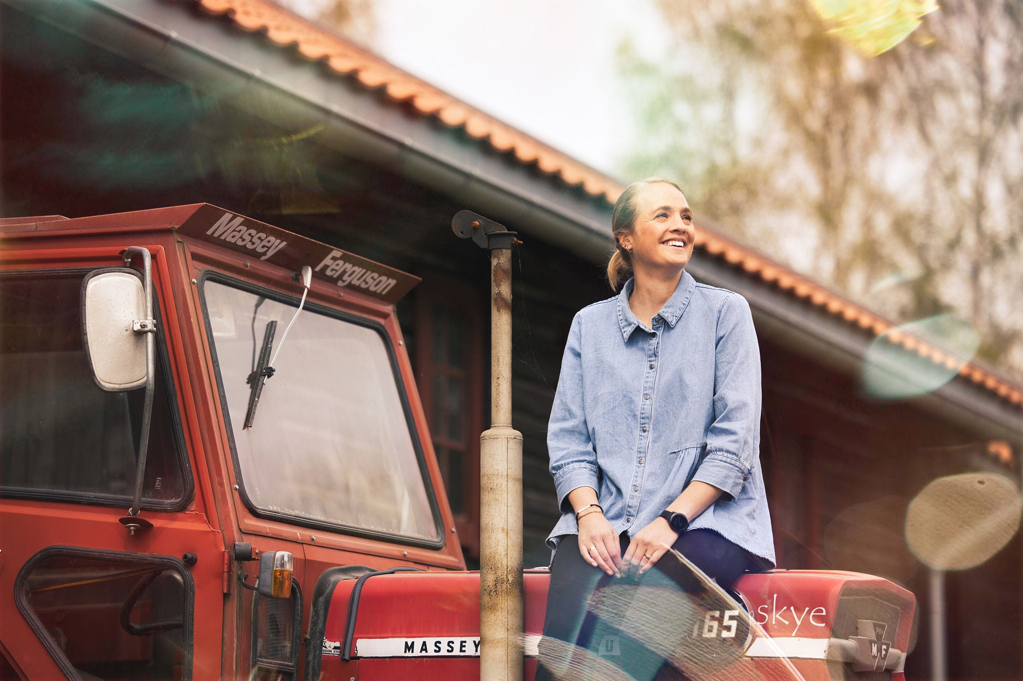 Miriam Melby sitter på en rød traktor, smiler og ser opp.