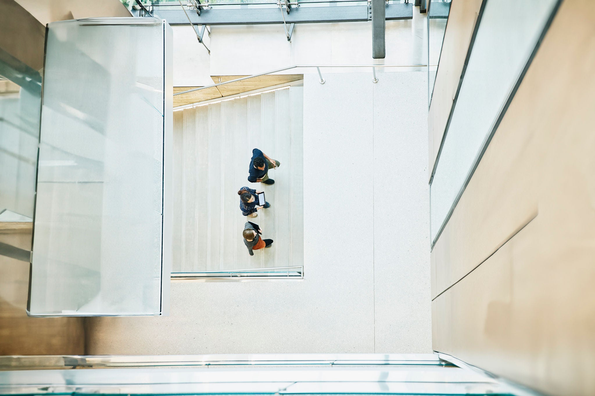 Overhead view of coworkers in discussion while walking up office stairs