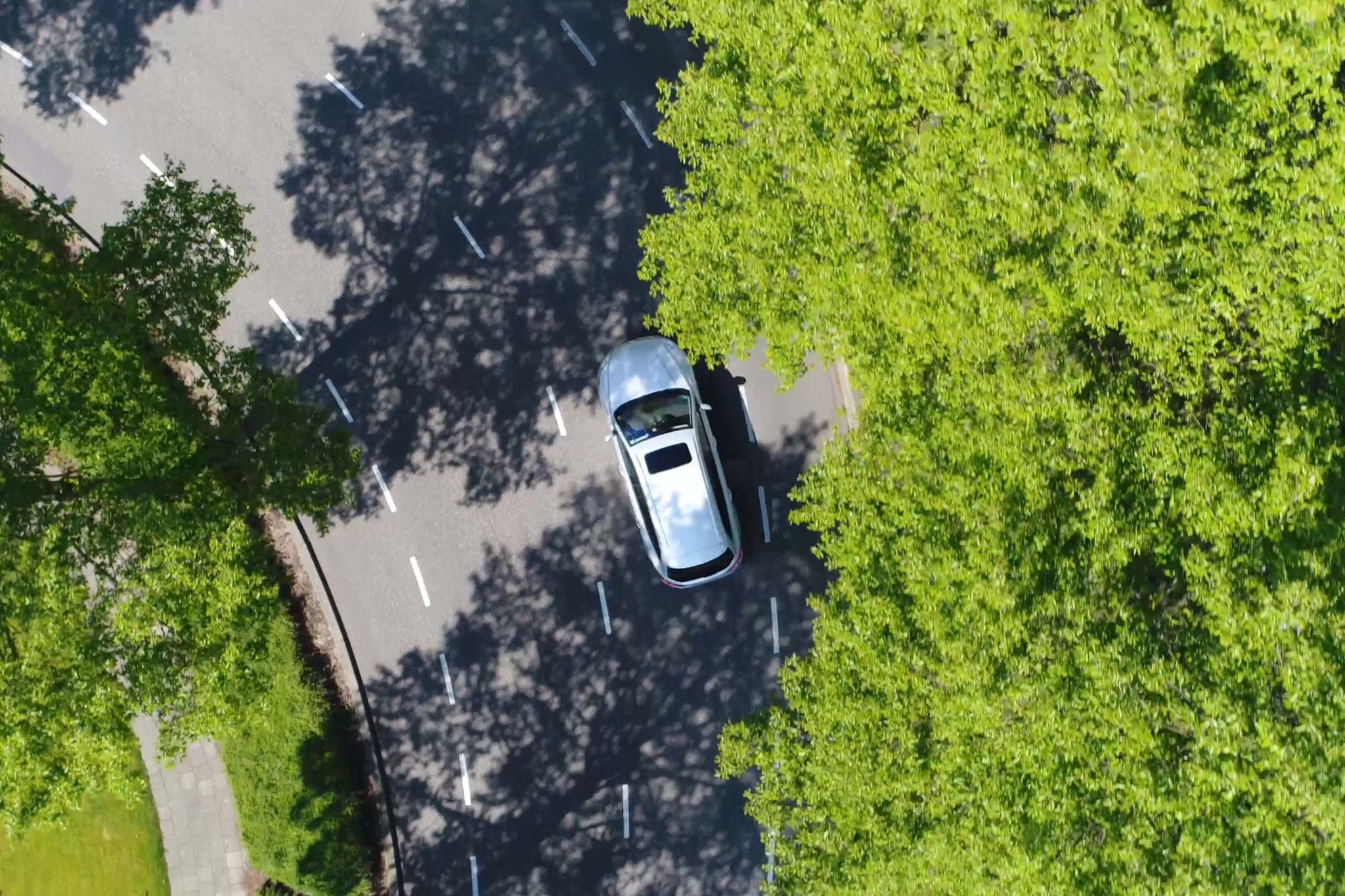 Aerial following car top-down view this grey colored station wagon is driving over two way street corner green trees on both sides of street; Shutterstock ID 655475707; charge: 67387960; job: A6169 - AM&M Business Minute podcast EP27; name: Charles Brewer; email: charles.brewer@uk.ey.com